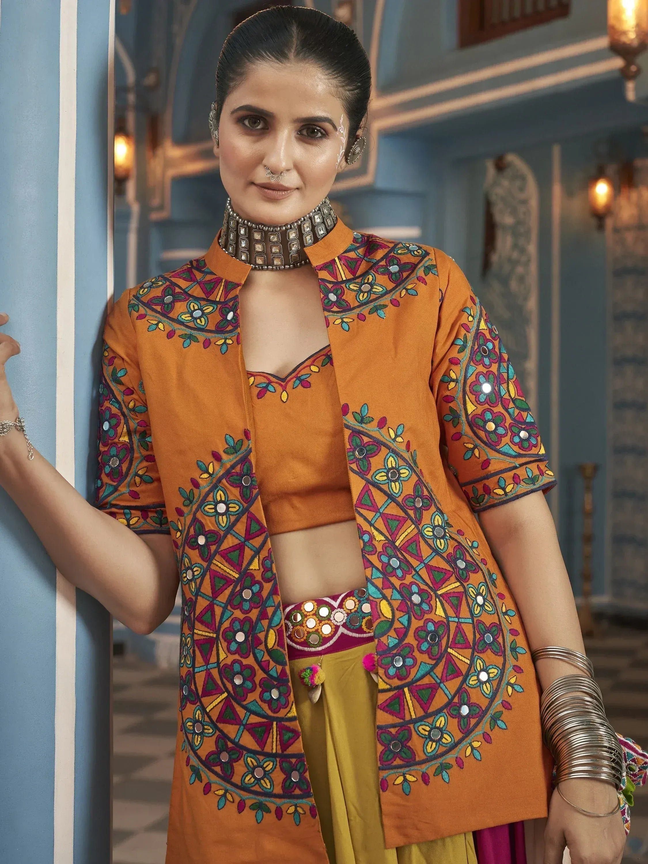 Orange embroidered ethnic jacket with mirror work, paired with crop top and palazzo pants for festive wear