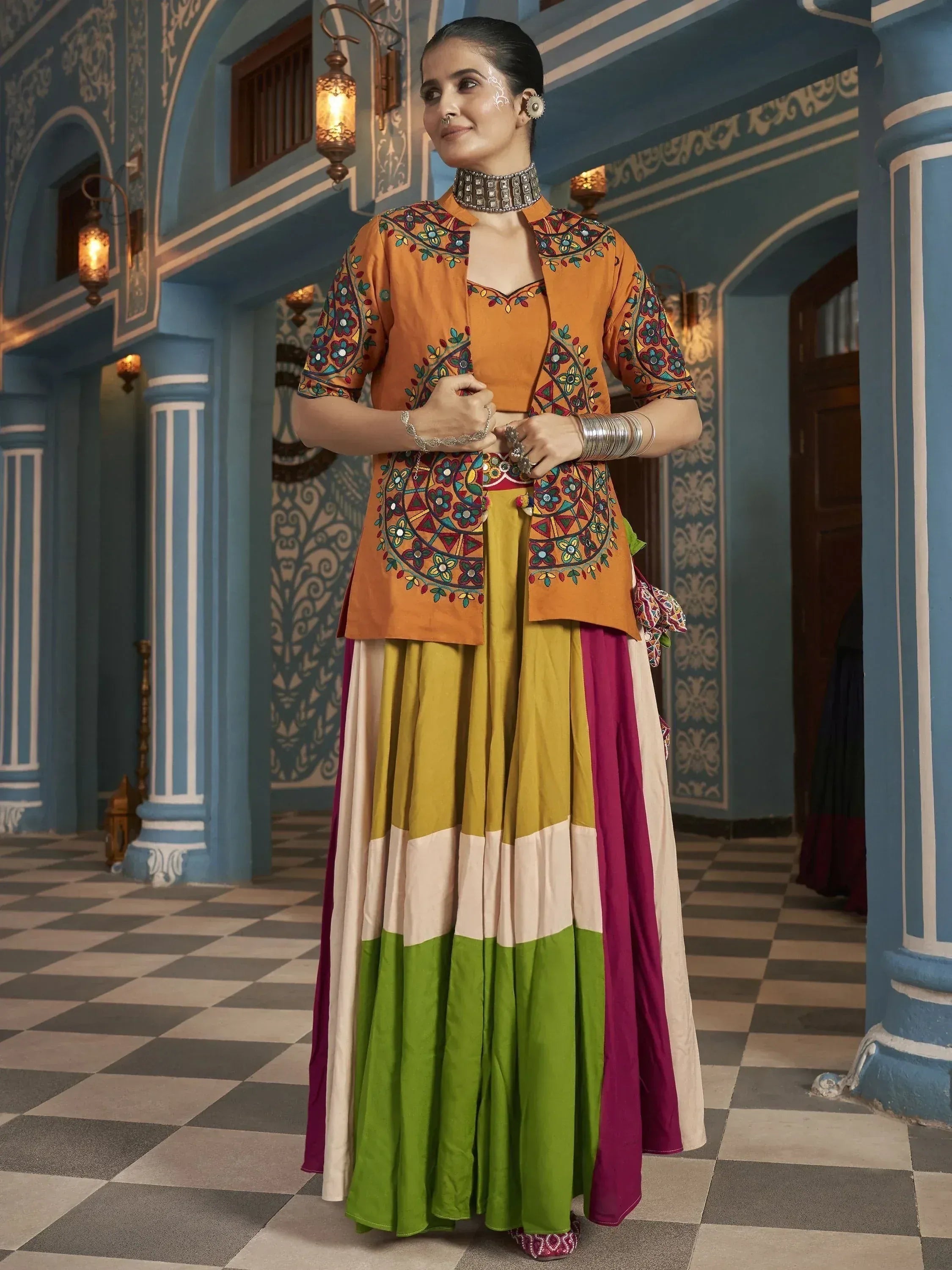 Woman in vibrant embroidered orange kurta with colorful panelled skirt, traditional Indian ethnic wear