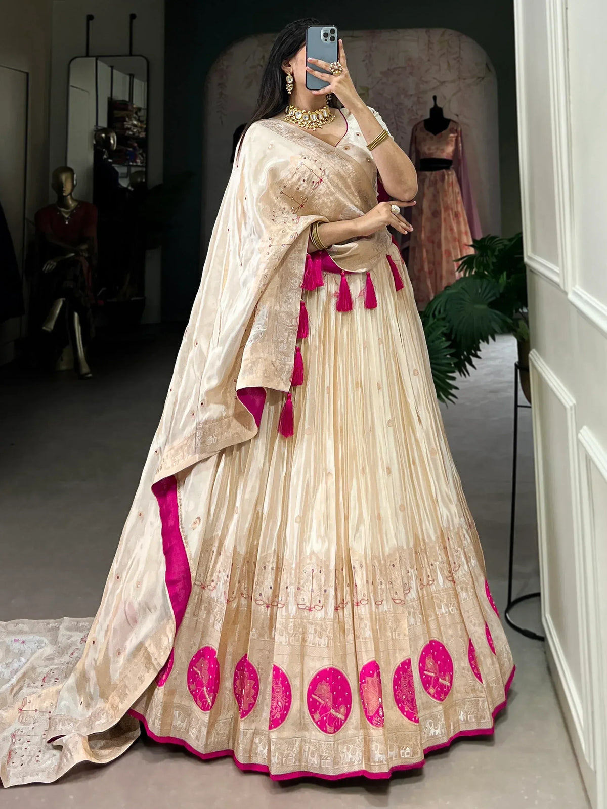 Cream and pink designer lehenga choli with embroidery and tassels, perfect for Indian weddings and festivals.