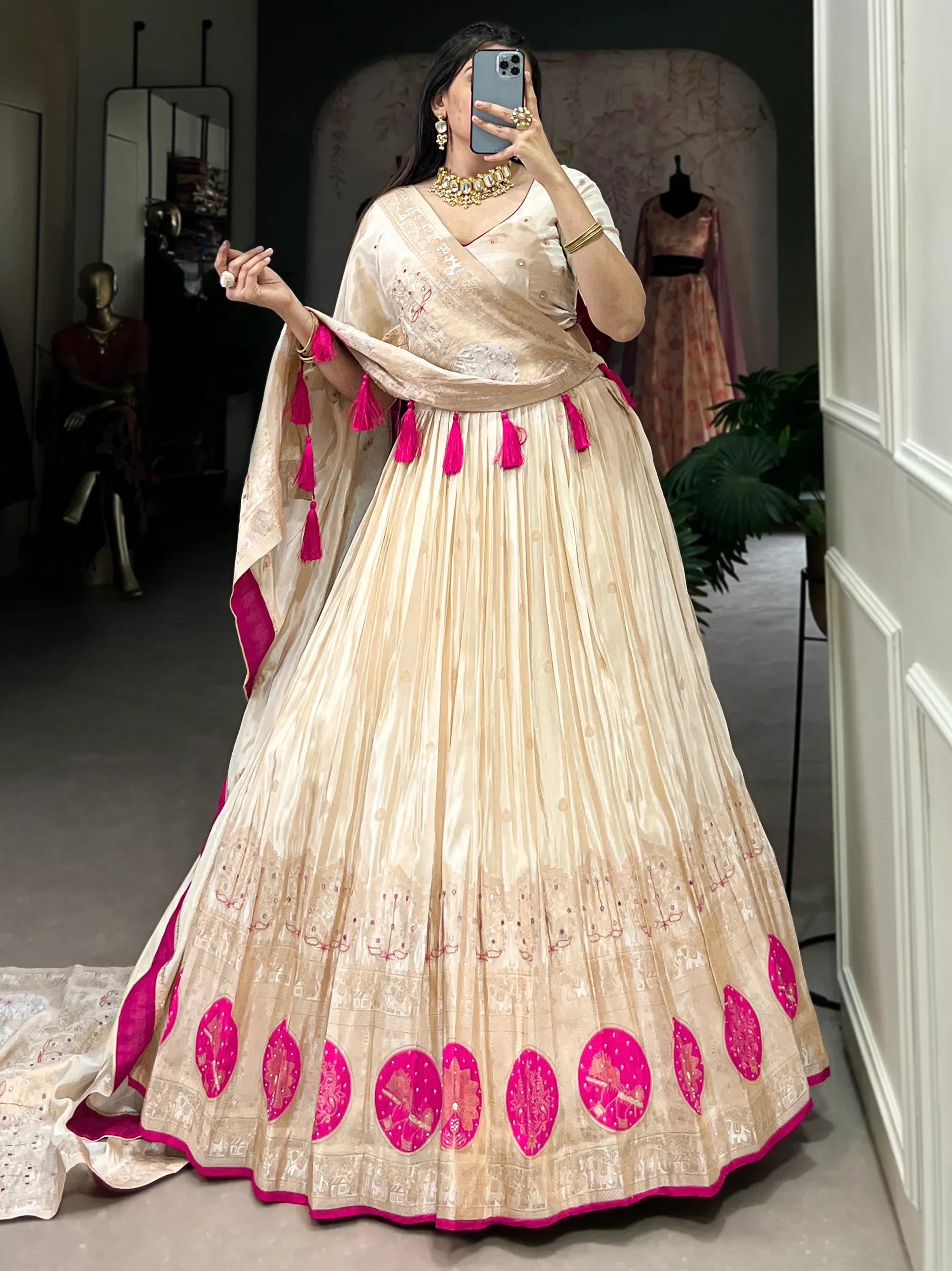 Cream and pink designer lehenga choli with tassels and embroidery, perfect for Indian weddings and festivals.