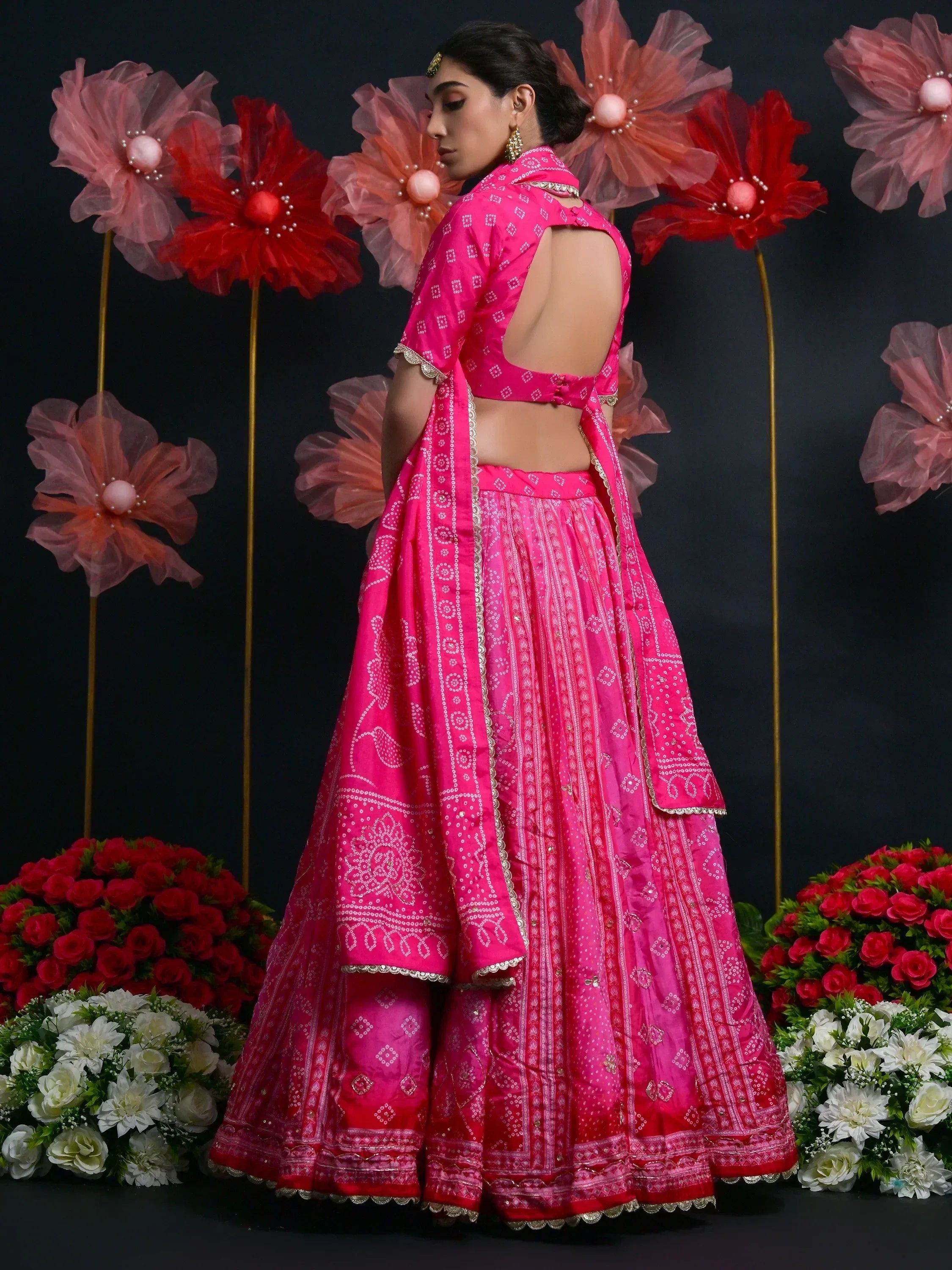 Pink designer lehenga choli with back cutout, floral backdrop, ethnic wear for weddings