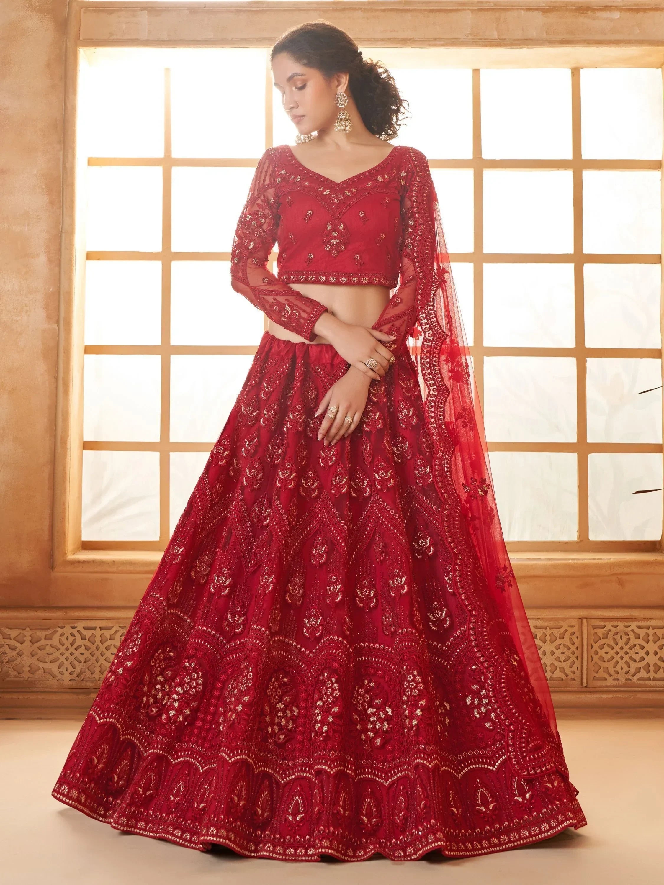 Red embroidered lehenga choli with sheer sleeves, perfect for Indian weddings and festive occasions.