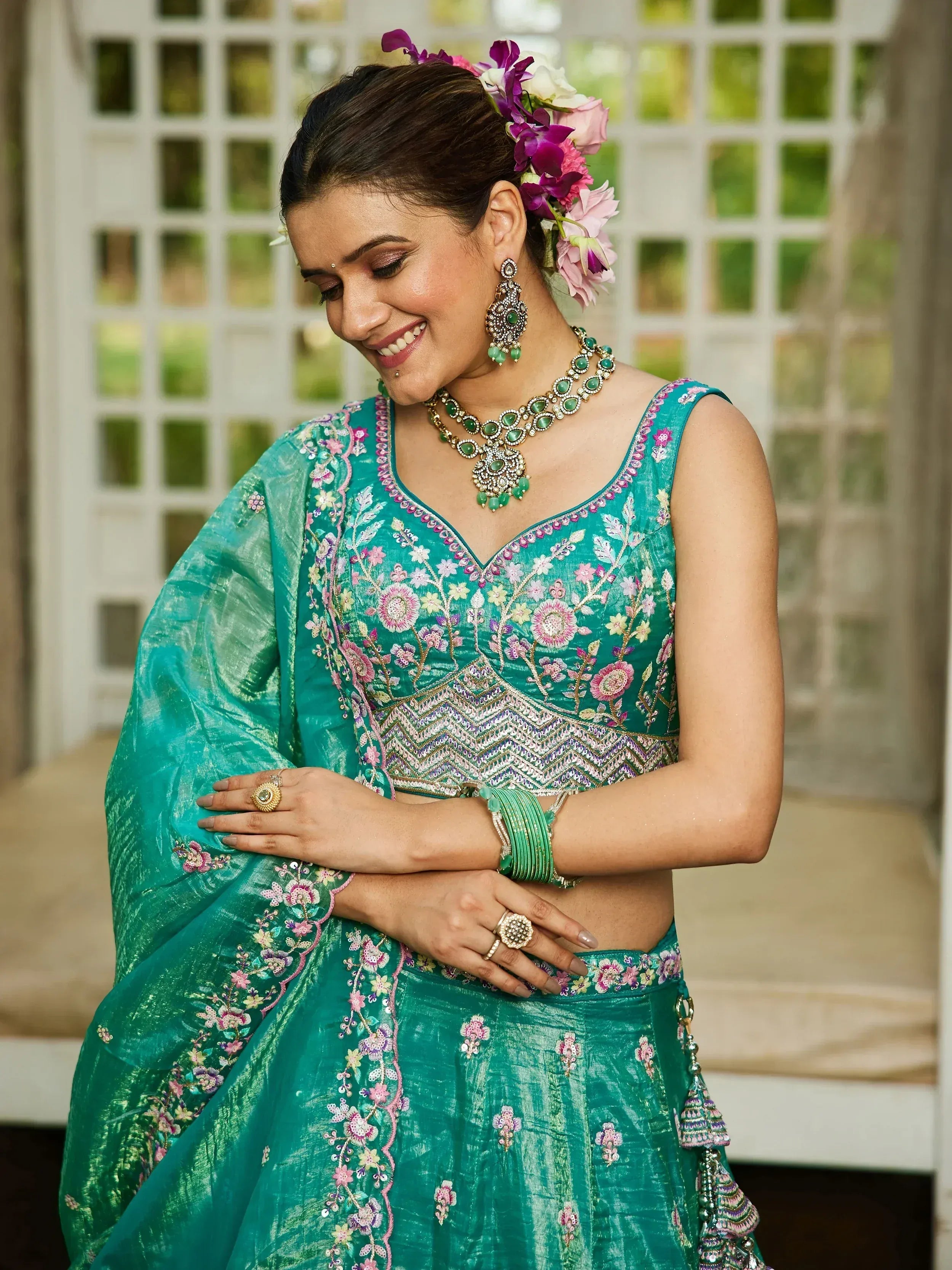 Teal floral embroidered lehenga choli with matching jewelry and floral hair accessory