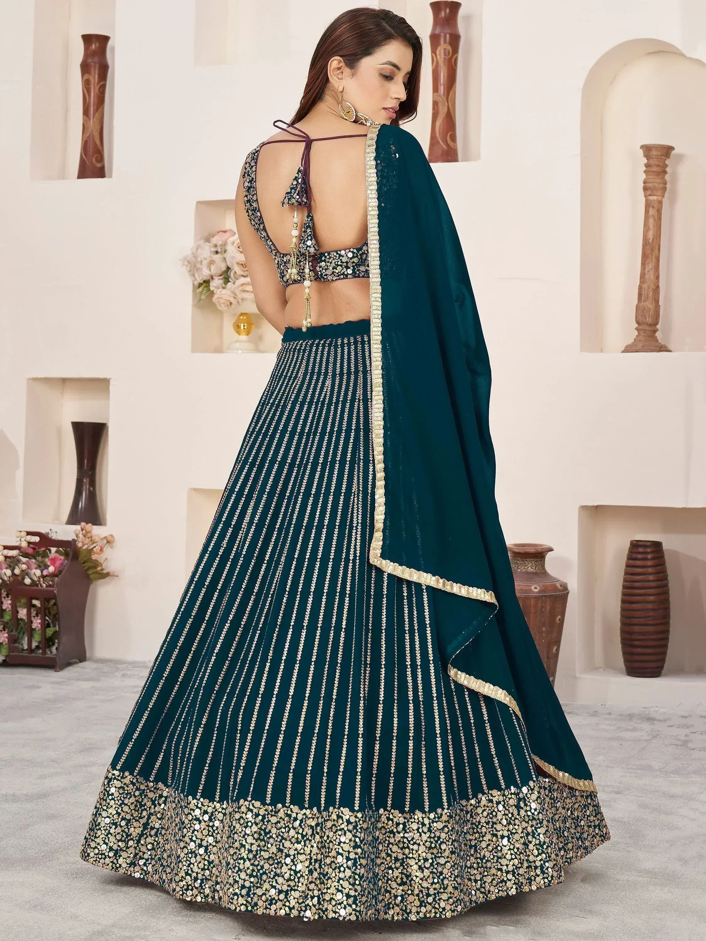 Teal designer lehenga choli with gold embroidery, sequins, and backless blouse for Indian ethnic wear