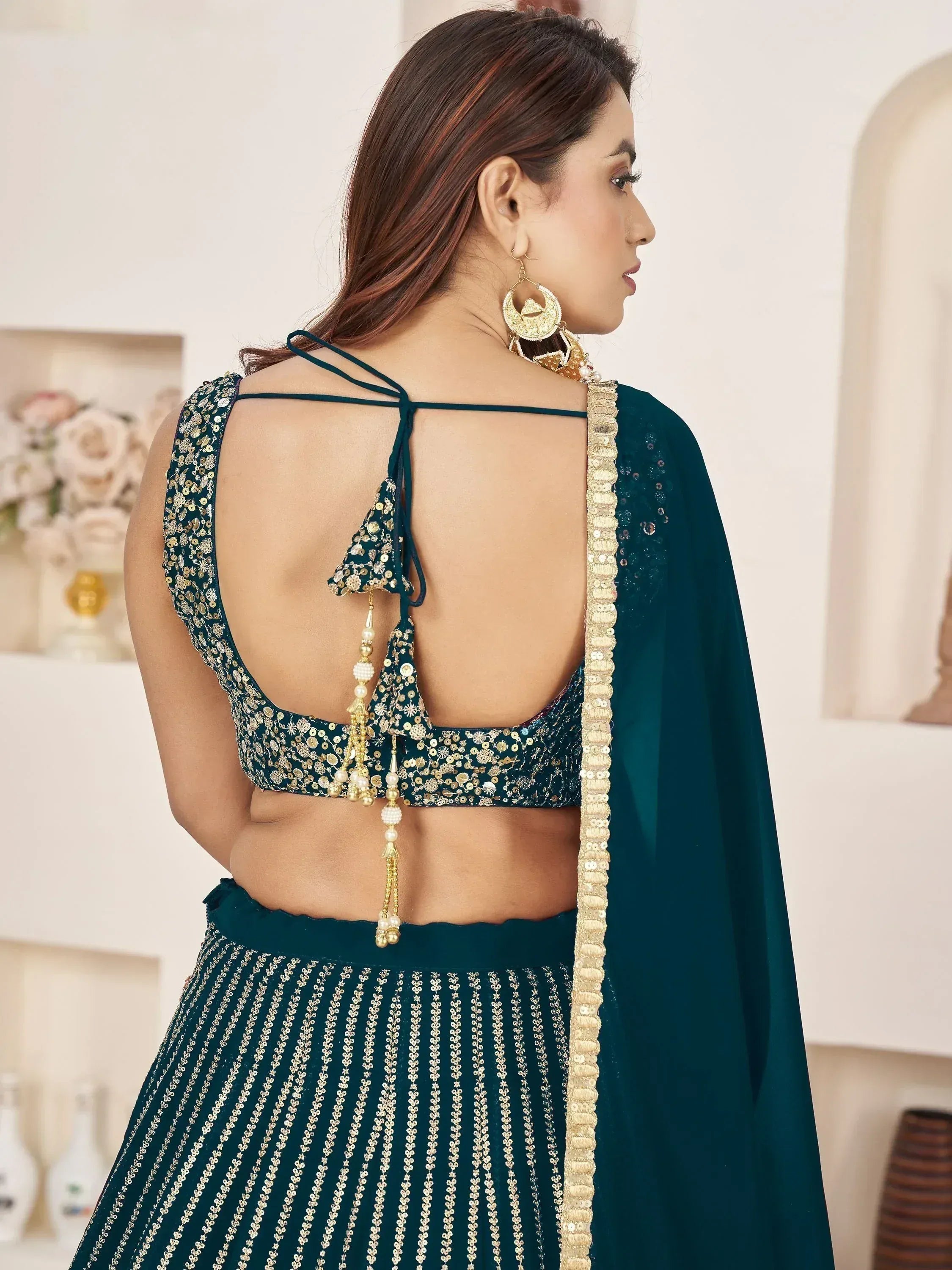Emerald green designer lehenga choli with sequin work, open back blouse, and gold tassels for Indian ethnic wear