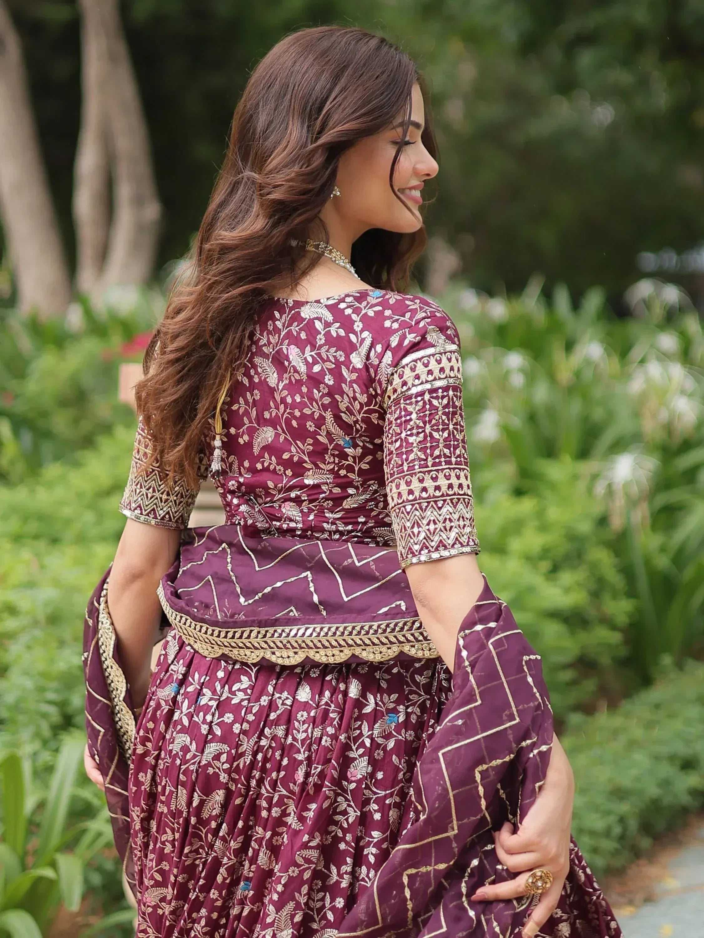 Woman in maroon embroidered lehenga choli with gold floral patterns, perfect for Indian ethnic wear occasions.