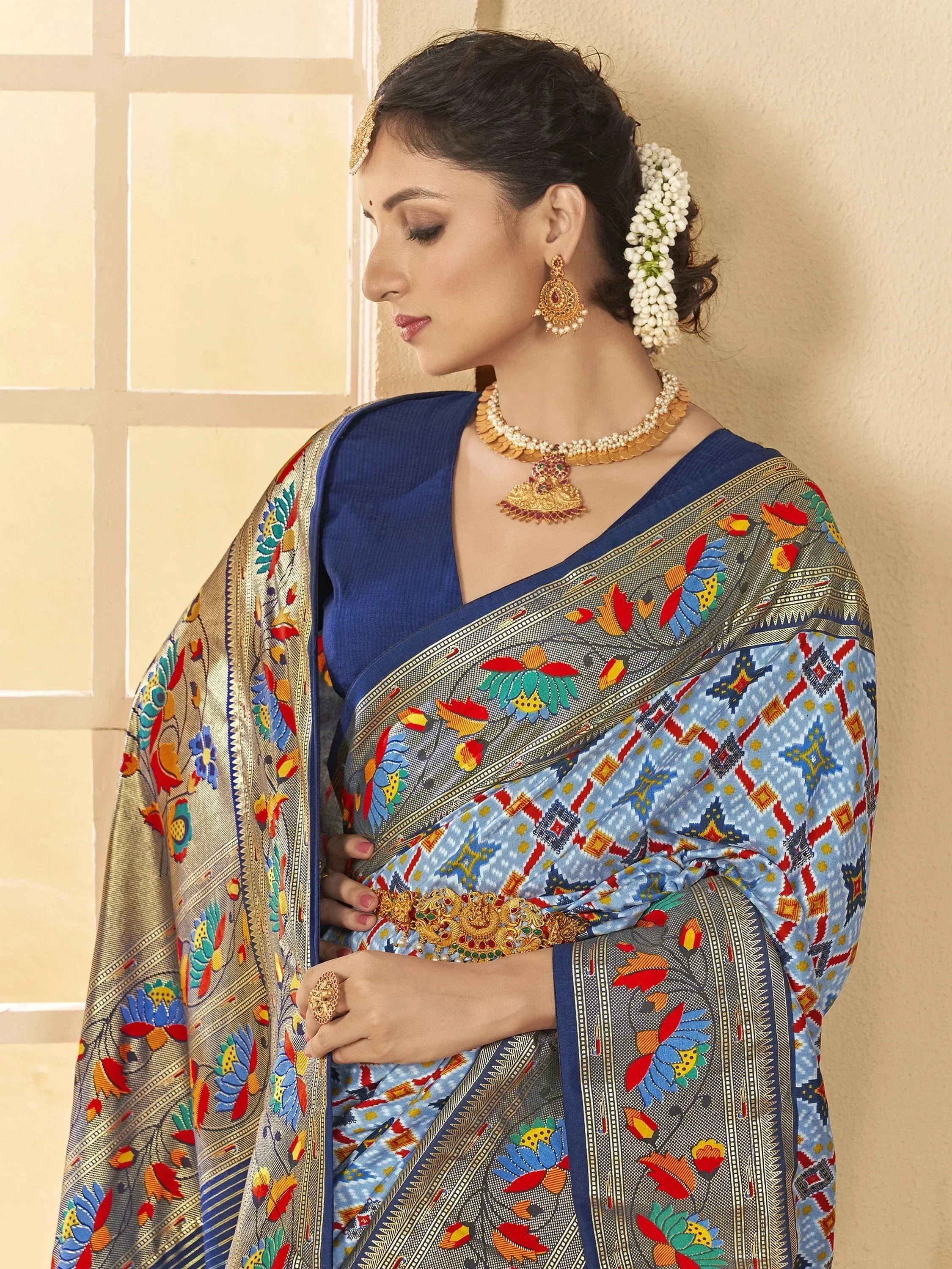Woman in vibrant printed saree with gold jewelry, traditional Indian ethnic wear