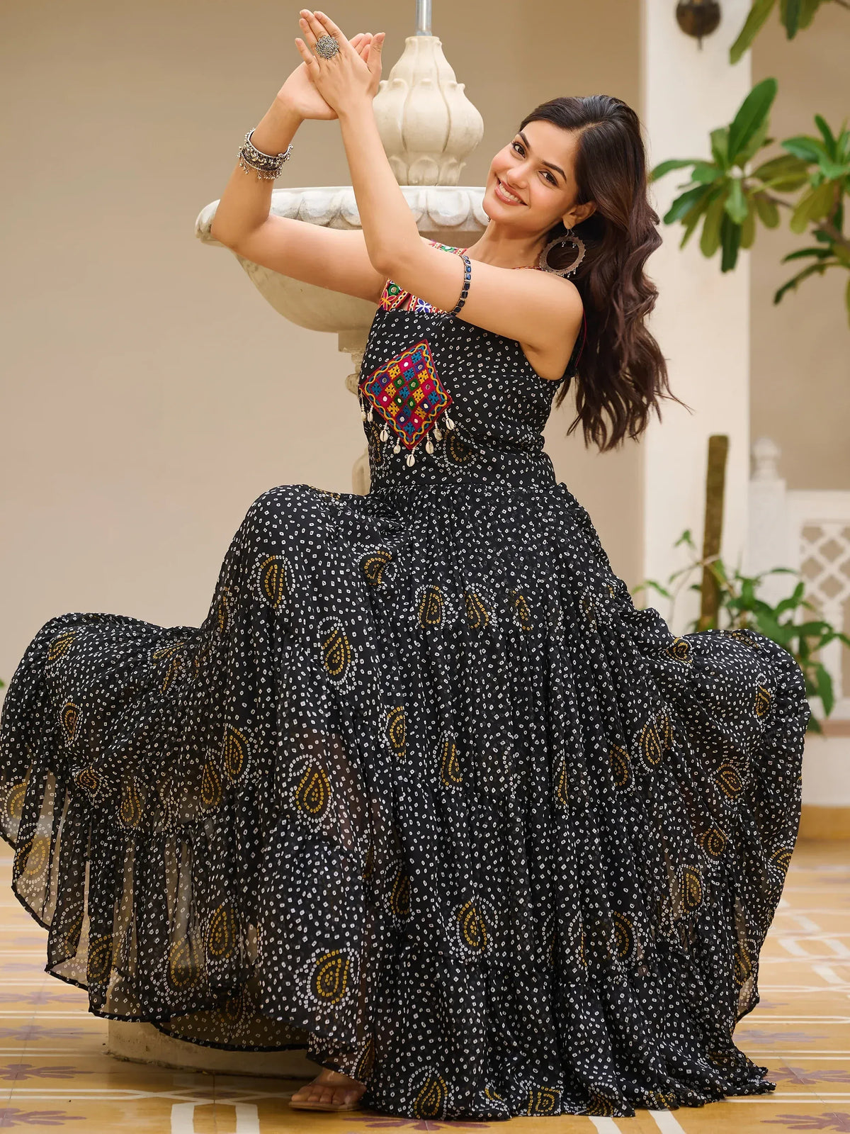 Woman in black printed ethnic gown with colorful embroidery, perfect for Indian festive occasions.