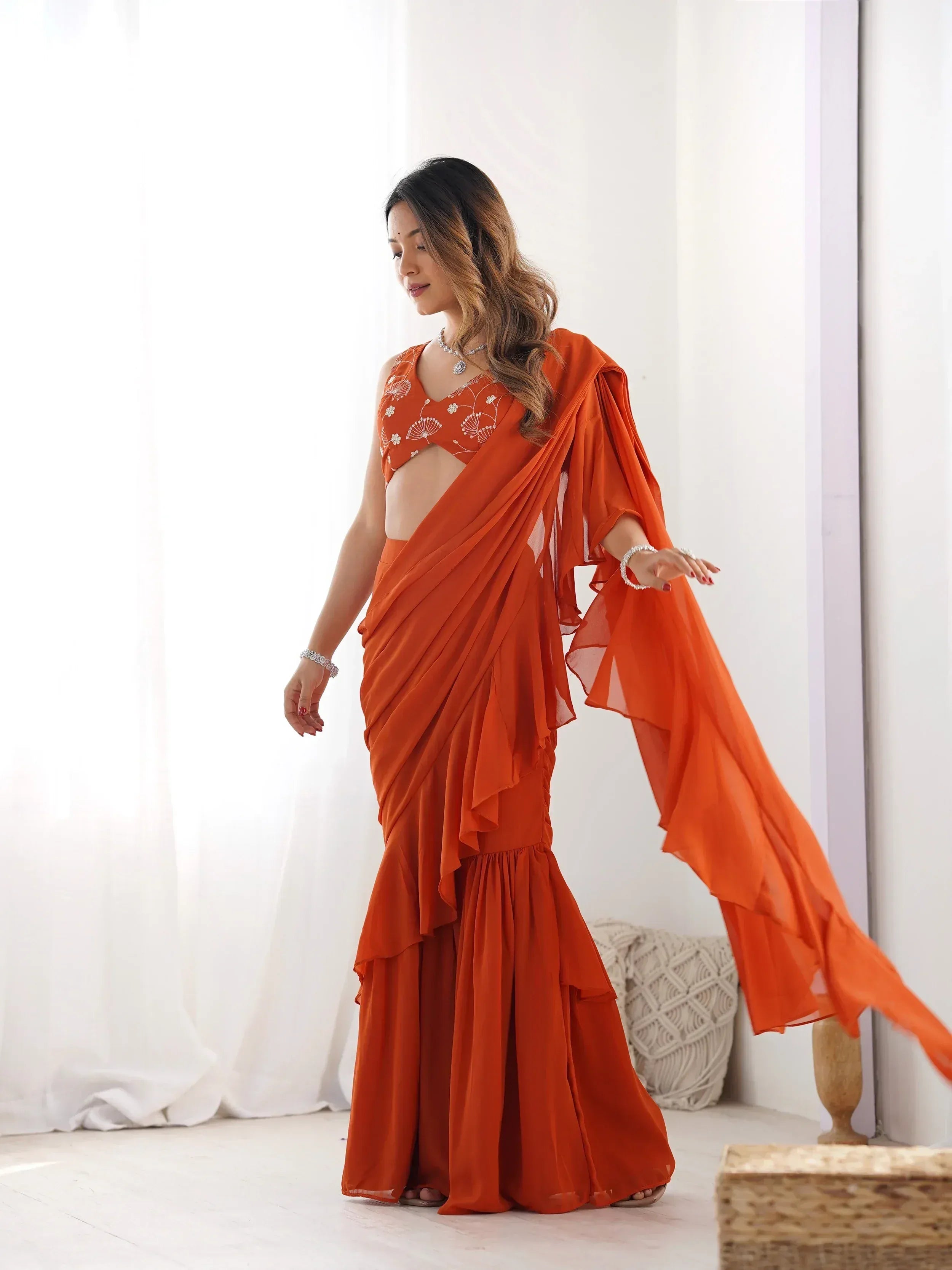 Orange ruffled saree gown with floral embroidery, perfect for Indian ethnic wear events