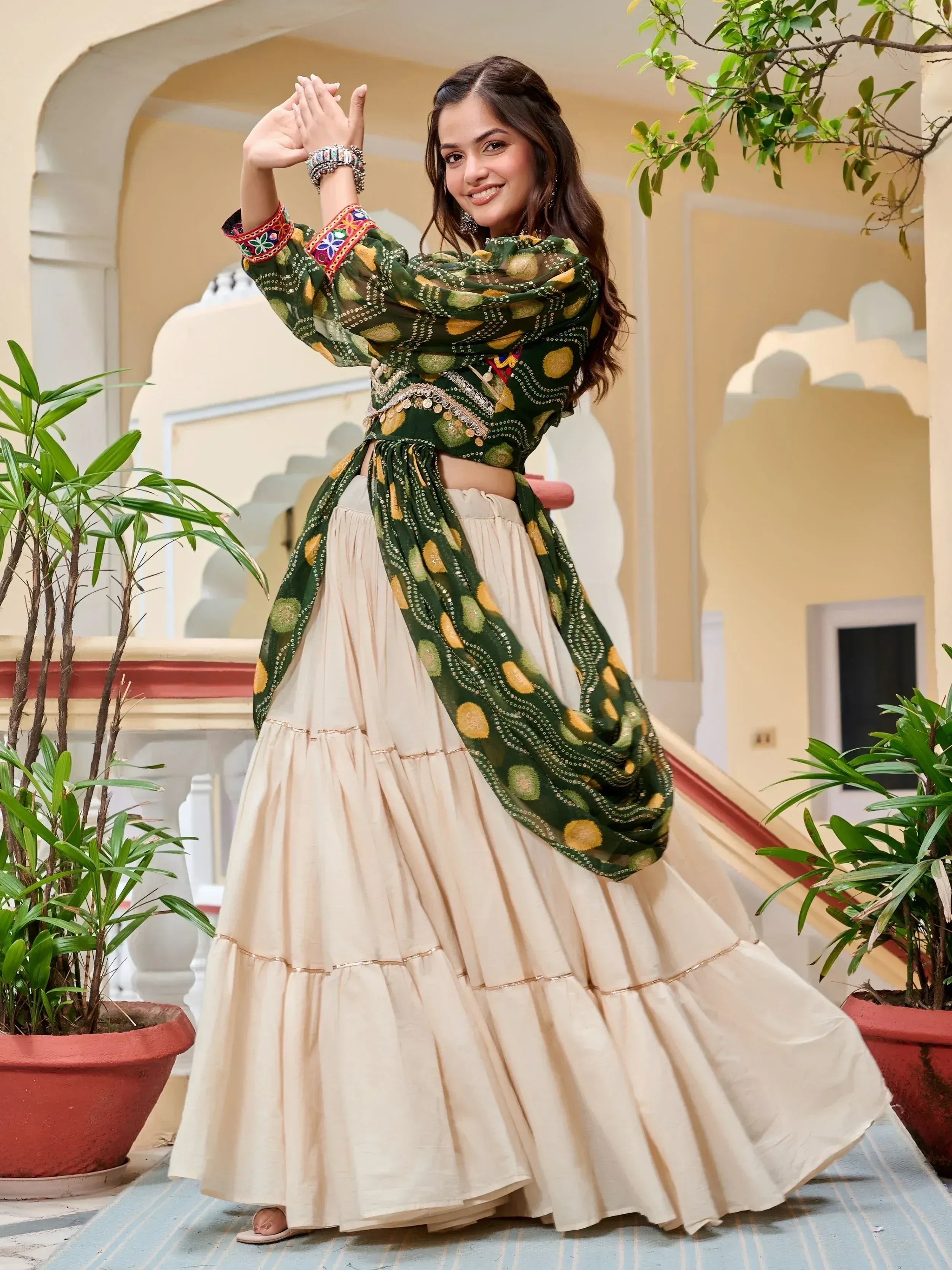 Woman in green embroidered crop top and cream tiered skirt, Indian ethnic wear for festive occasions