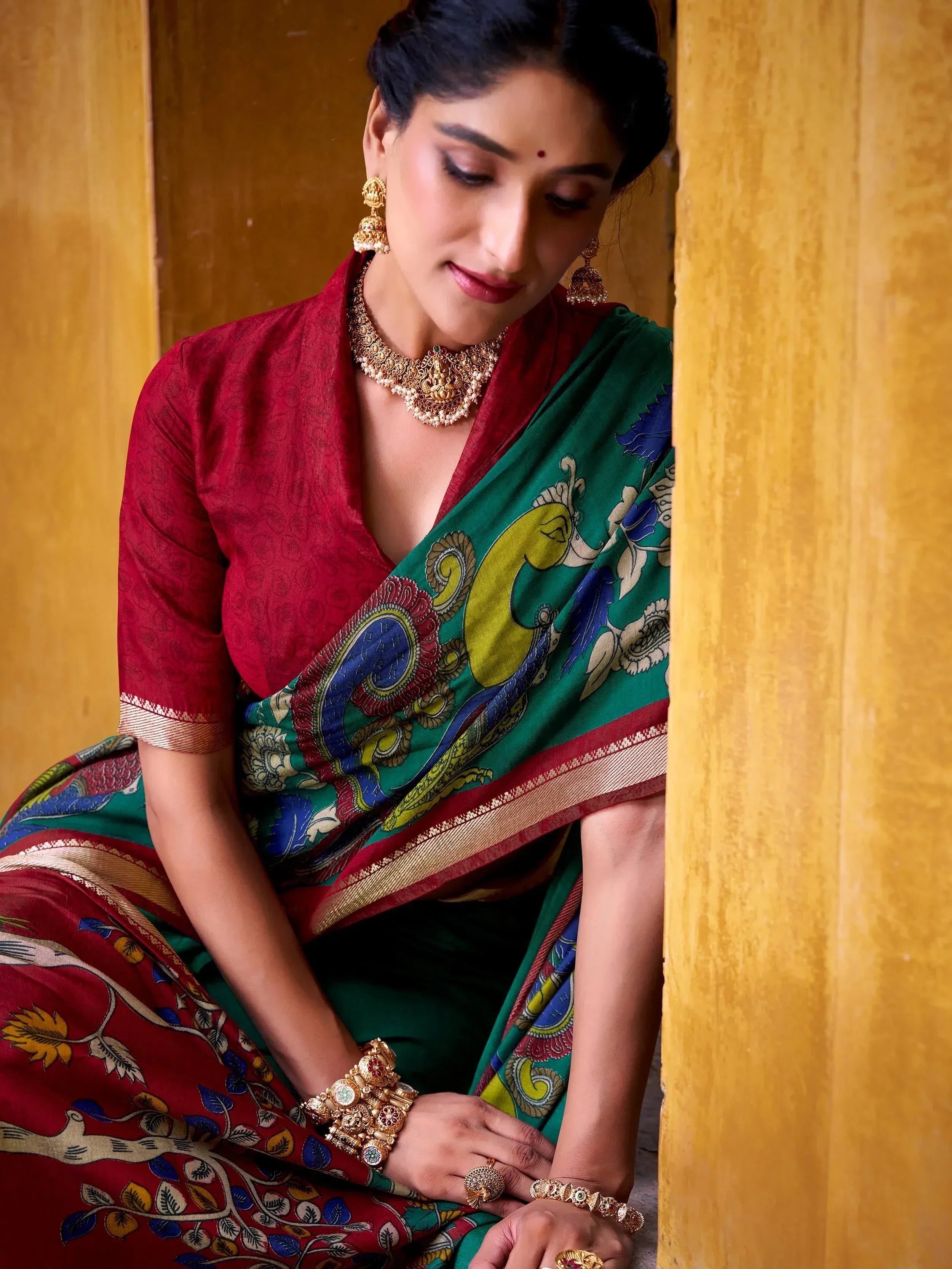 Woman in green and red printed saree with gold jewelry, traditional Indian ethnic wear