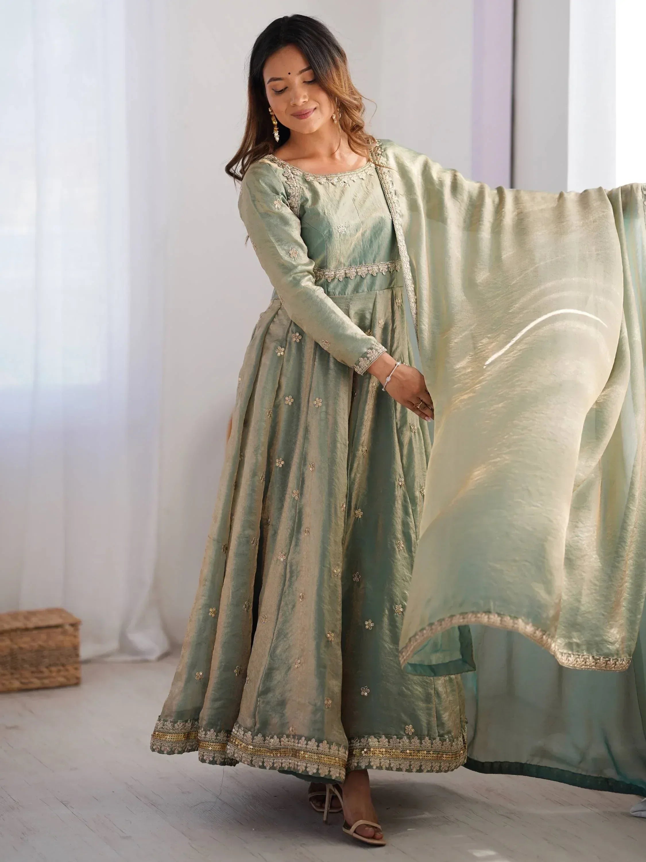 Woman wearing pastel green embroidered ethnic gown with dupatta in bright room