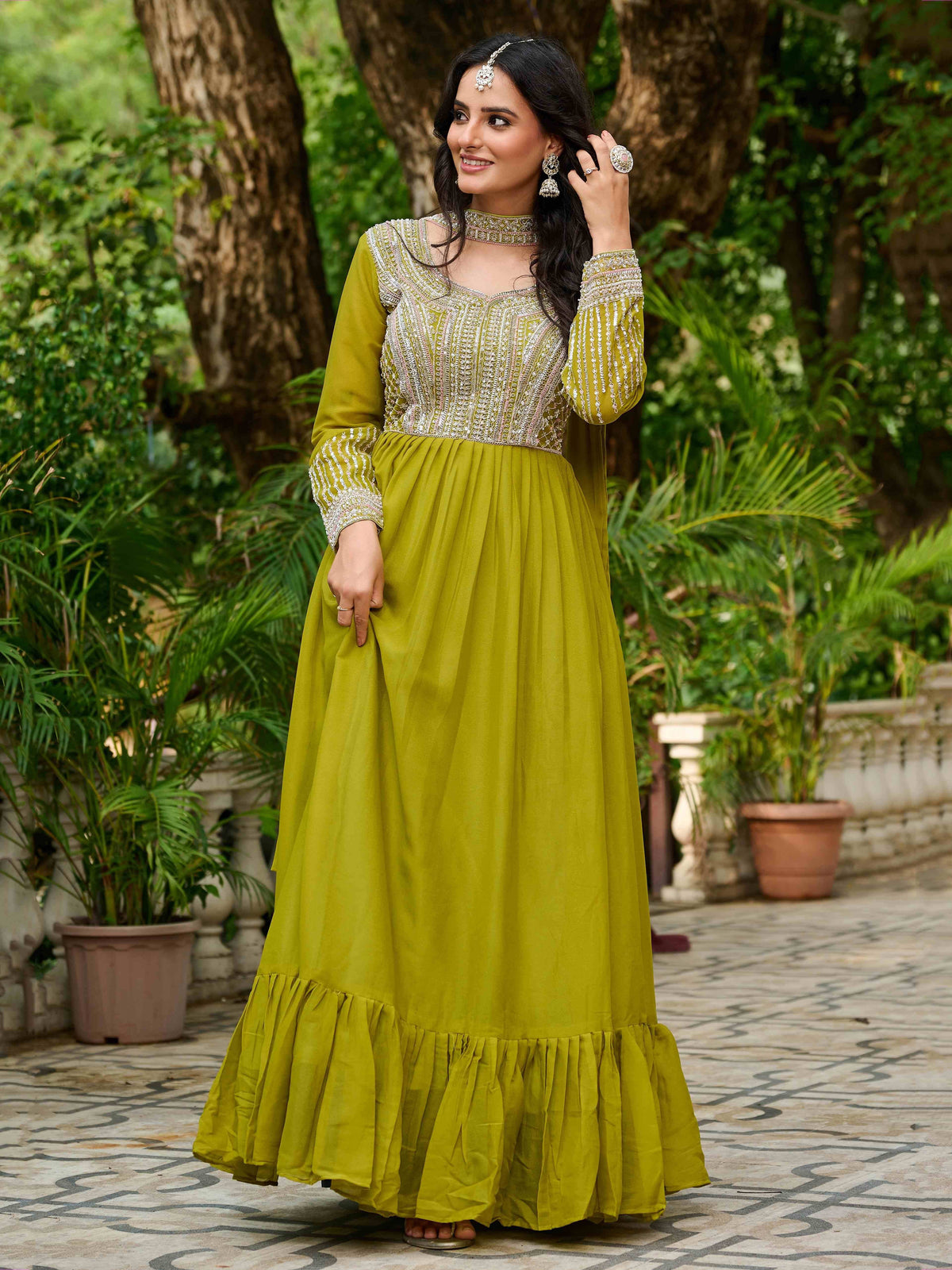Woman in olive green embroidered ethnic gown with ruffled hem, perfect for Indian occasions