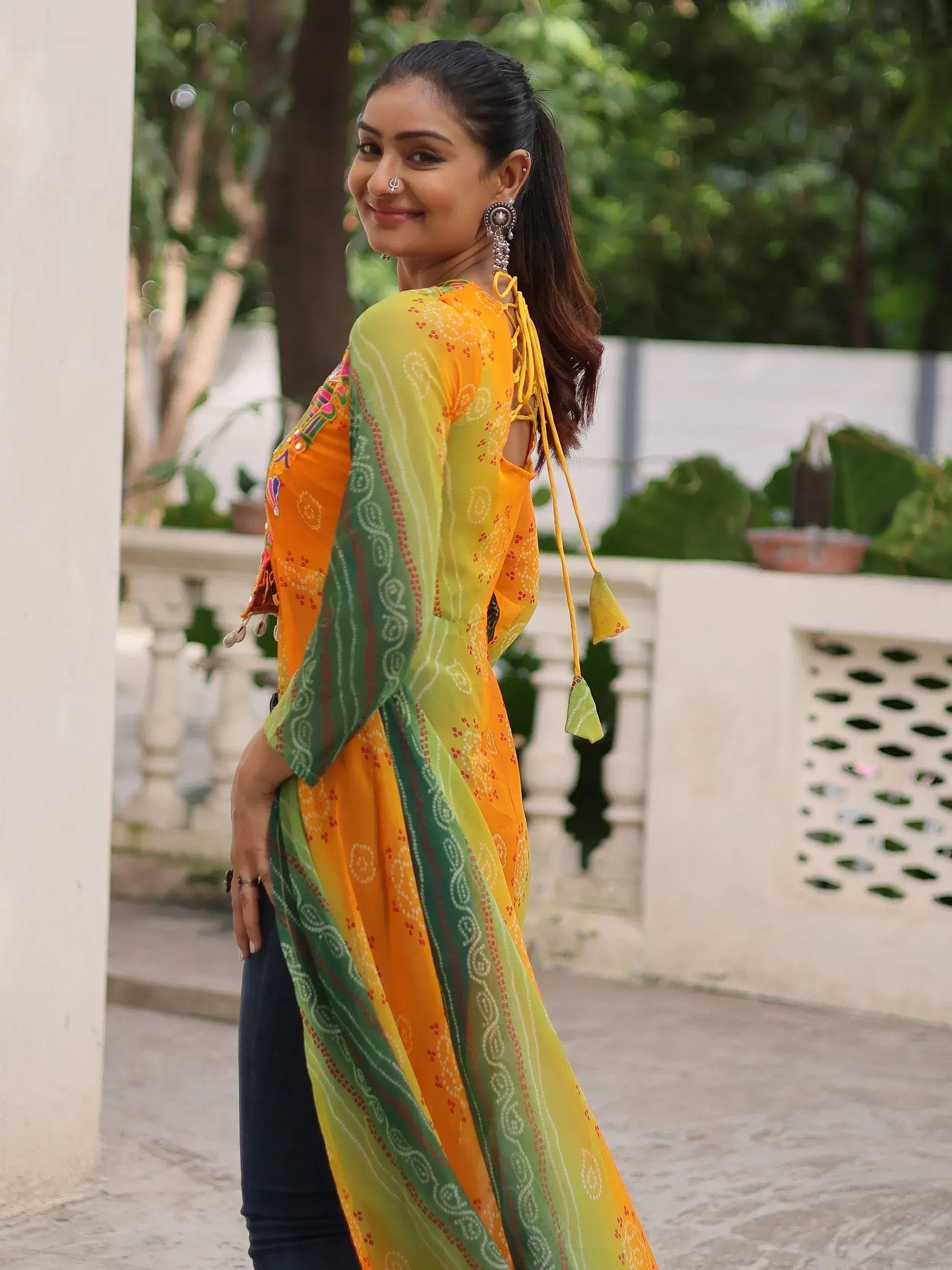 Woman in vibrant yellow and green printed ethnic kurta with tie-back detail, styled with jeans for casual wear