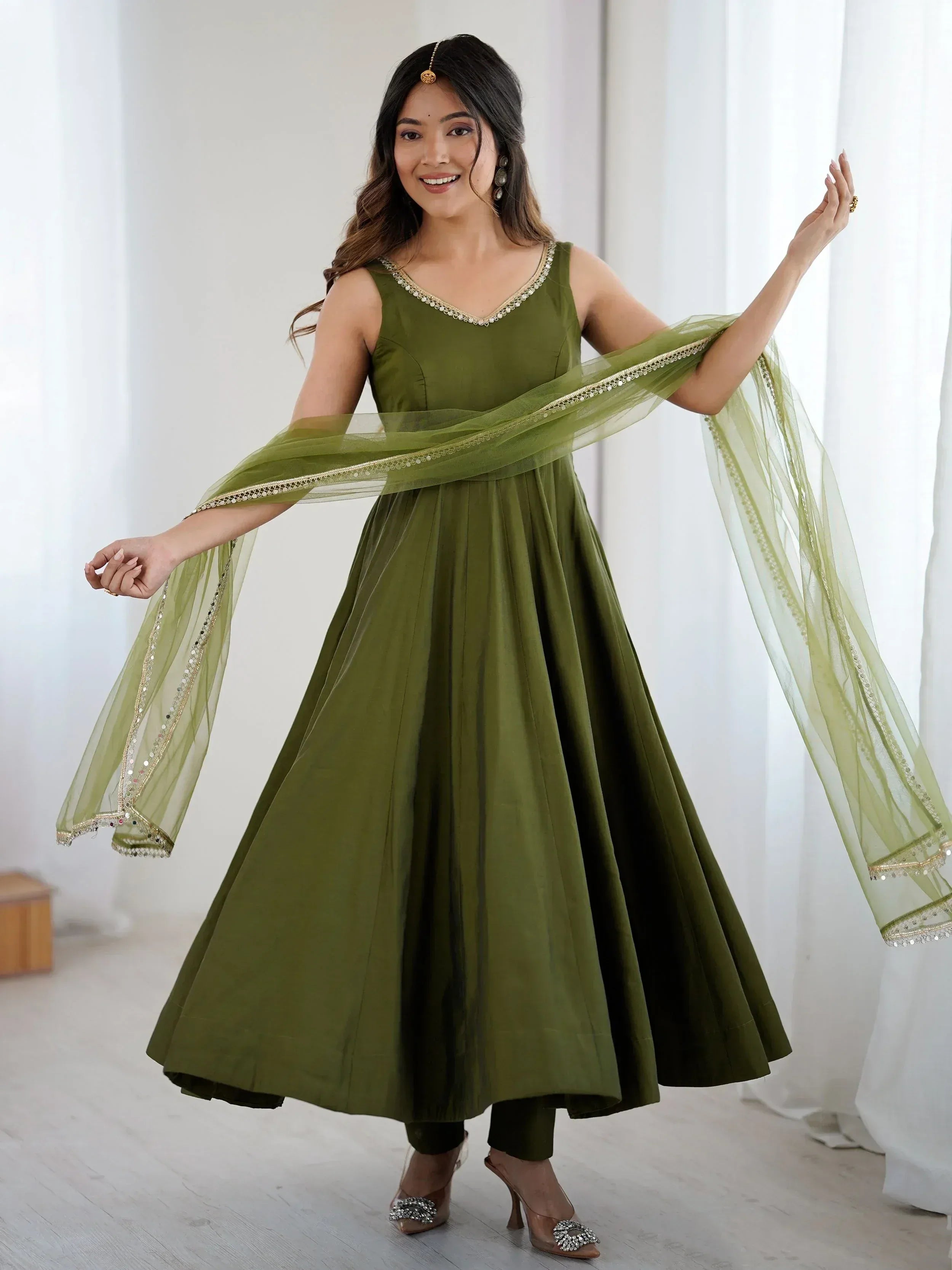 Olive green ethnic anarkali gown with gold trim and sheer dupatta, perfect for Indian festive occasions.