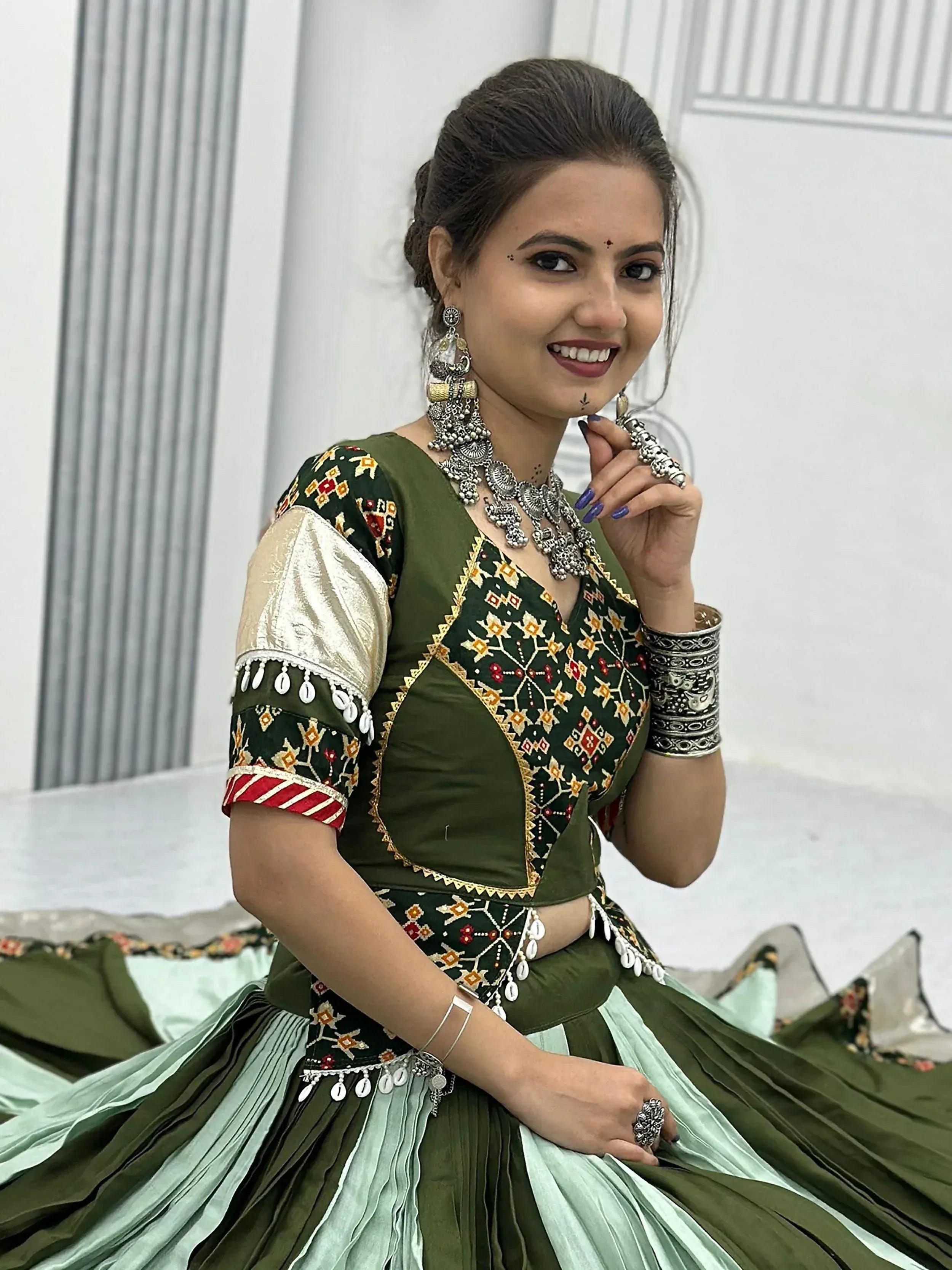 Woman in olive green embroidered lehenga choli with silver jewelry, perfect for Indian ethnic wear occasions