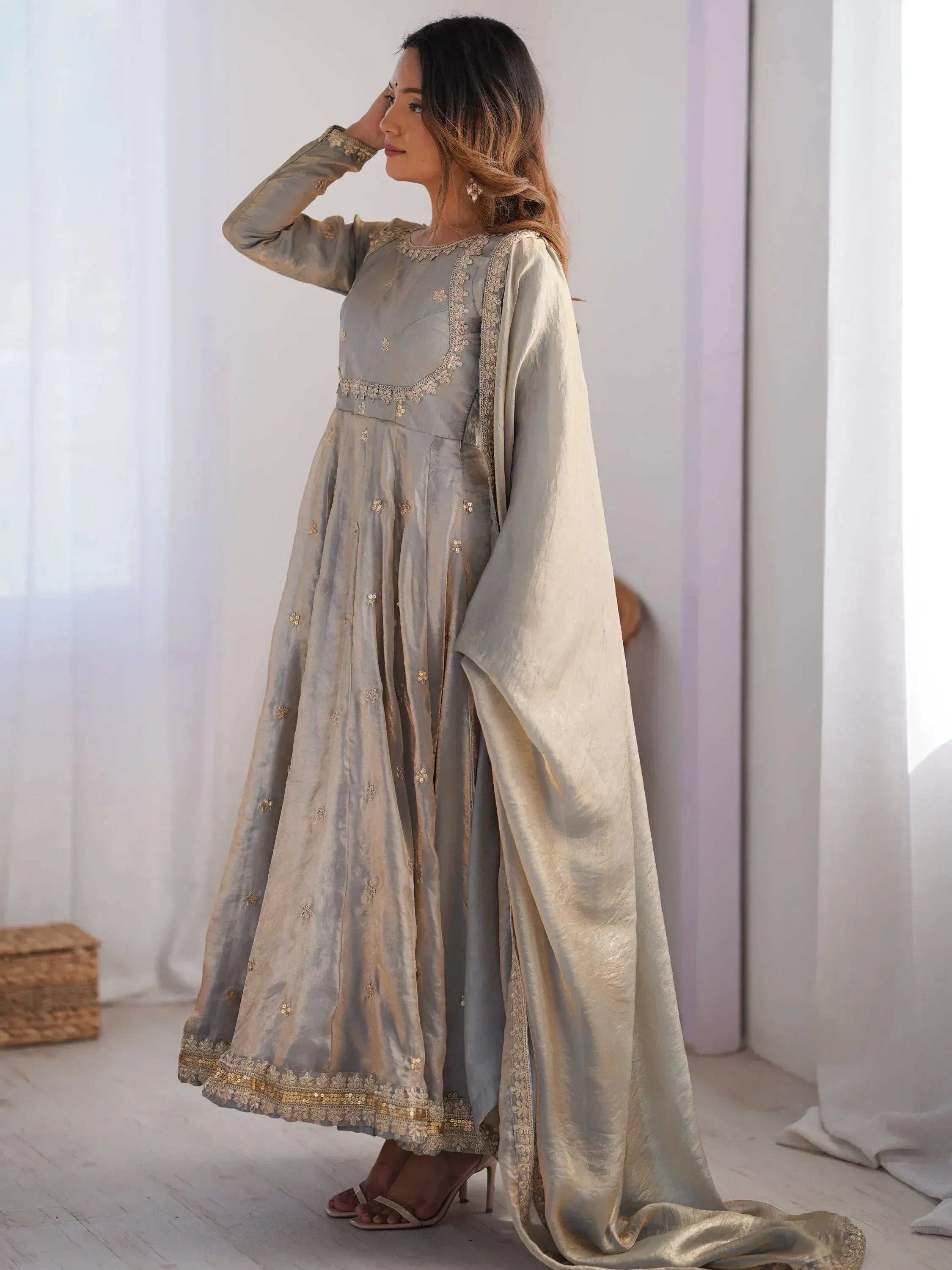 Woman wearing a grey embroidered ethnic gown with dupatta in a bright indoor setting