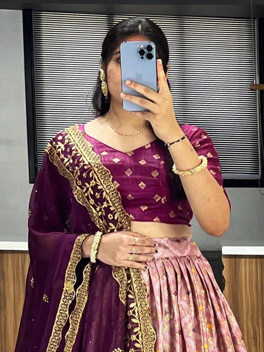 Woman in purple and pink designer lehenga choli with gold embroidery, taking mirror selfie