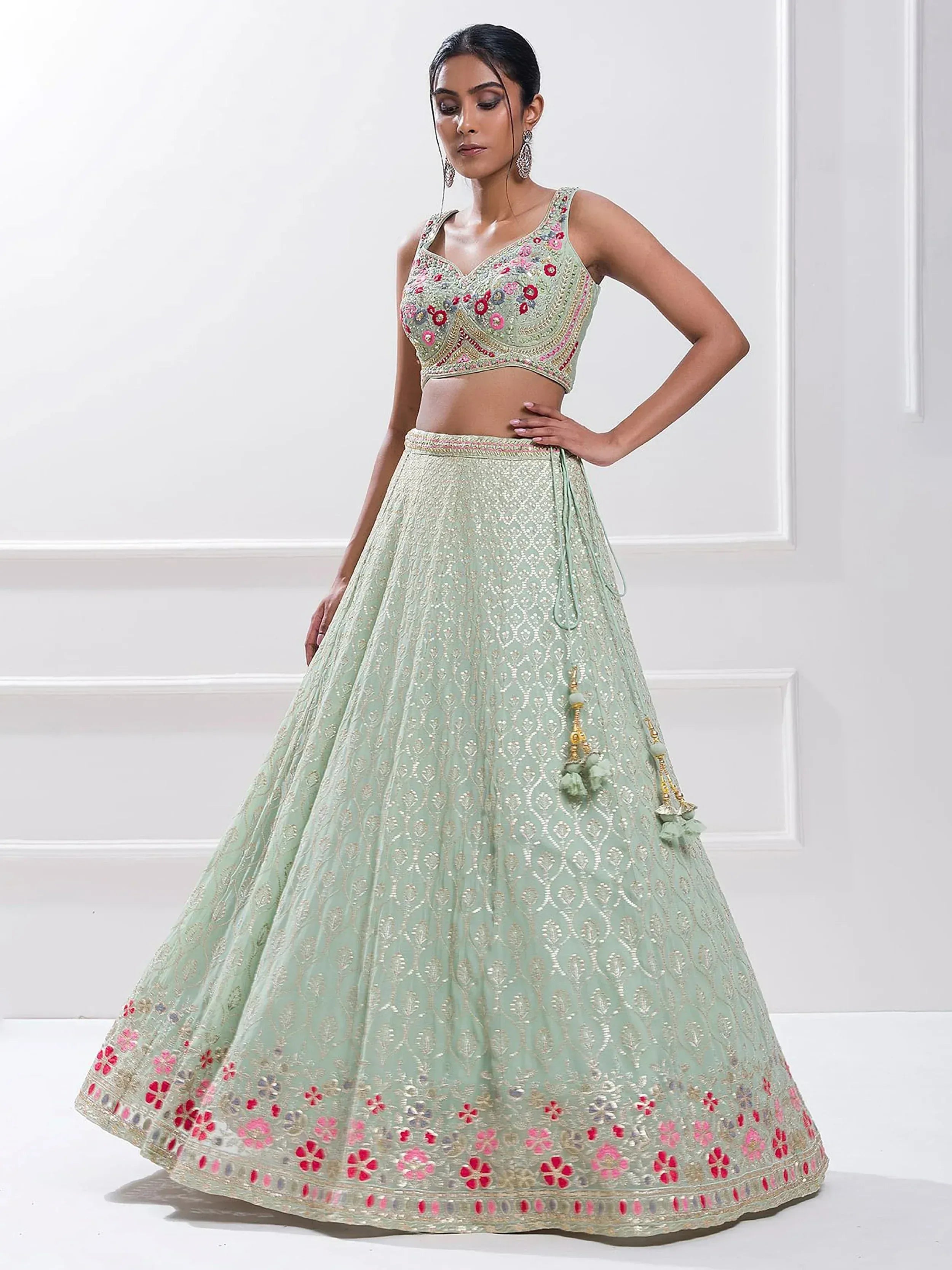 Mint green embroidered lehenga choli with floral motifs and tassels, perfect for Indian ethnic wear occasions.