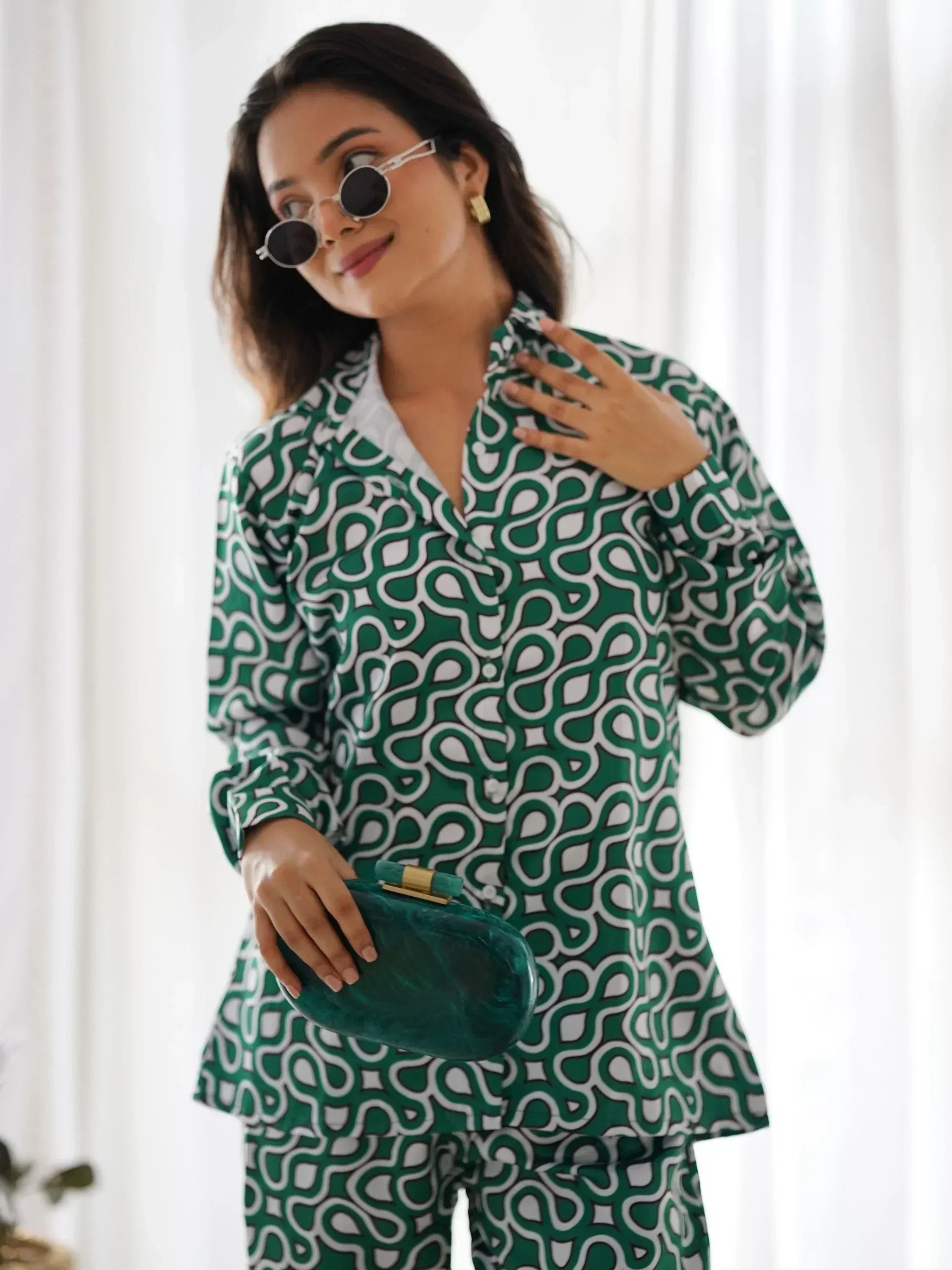 Woman in green and white geometric print ethnic co-ord set holding green clutch
