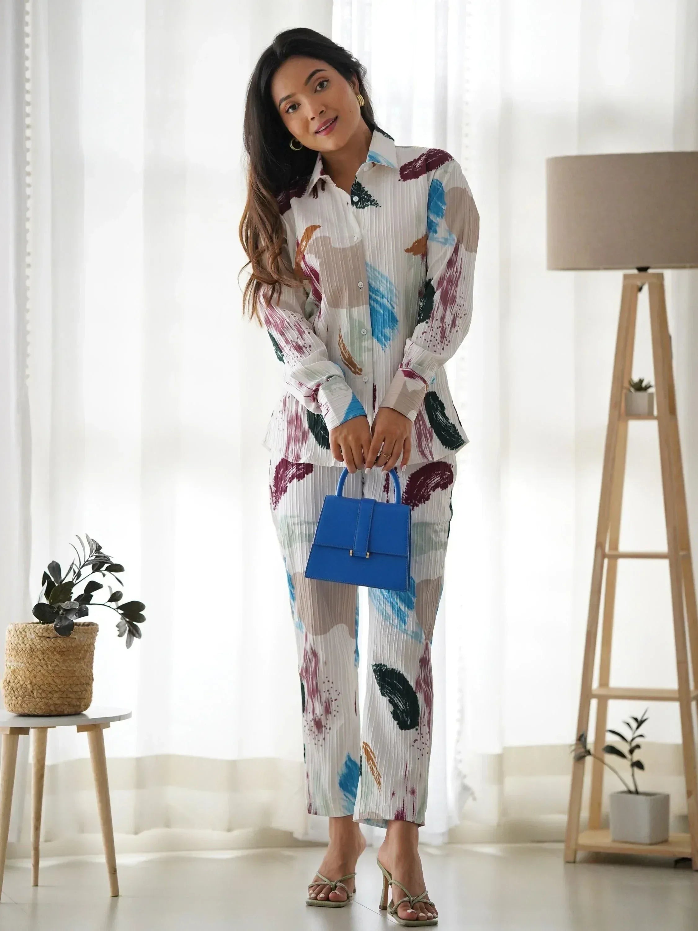 Woman in printed ethnic pantsuit with blue handbag, stylish Indian wear for modern occasions