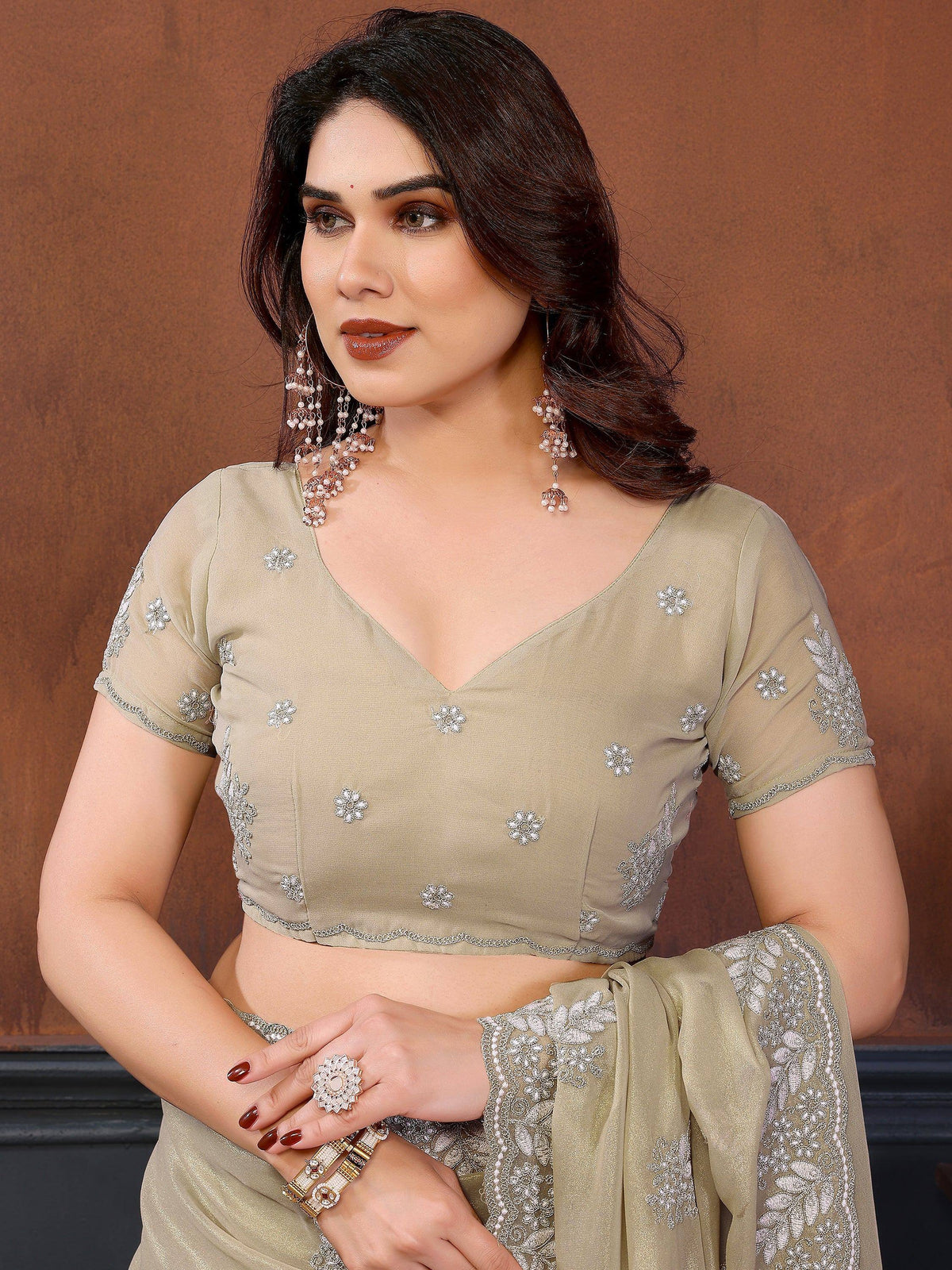 Woman wearing a beige designer lehenga choli with silver floral embroidery