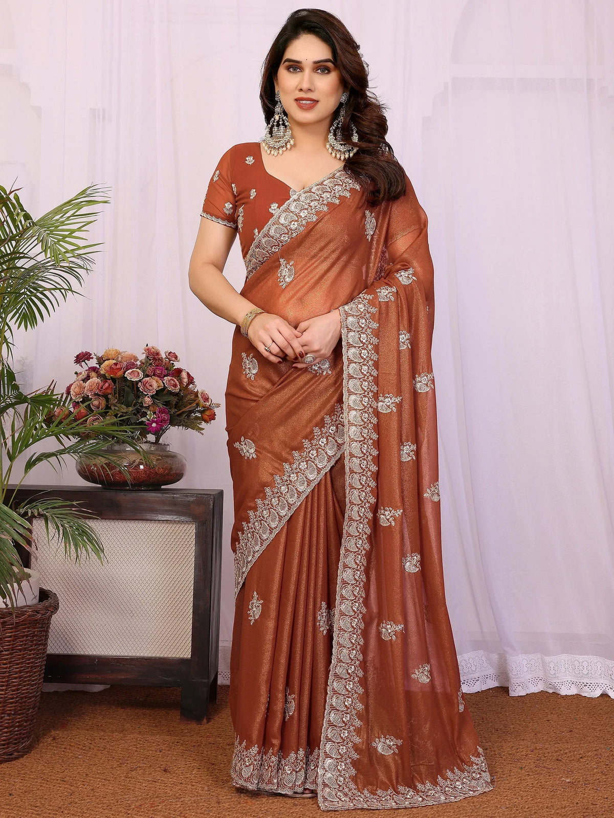 Woman wearing a brown designer saree with intricate silver embroidery and matching blouse
