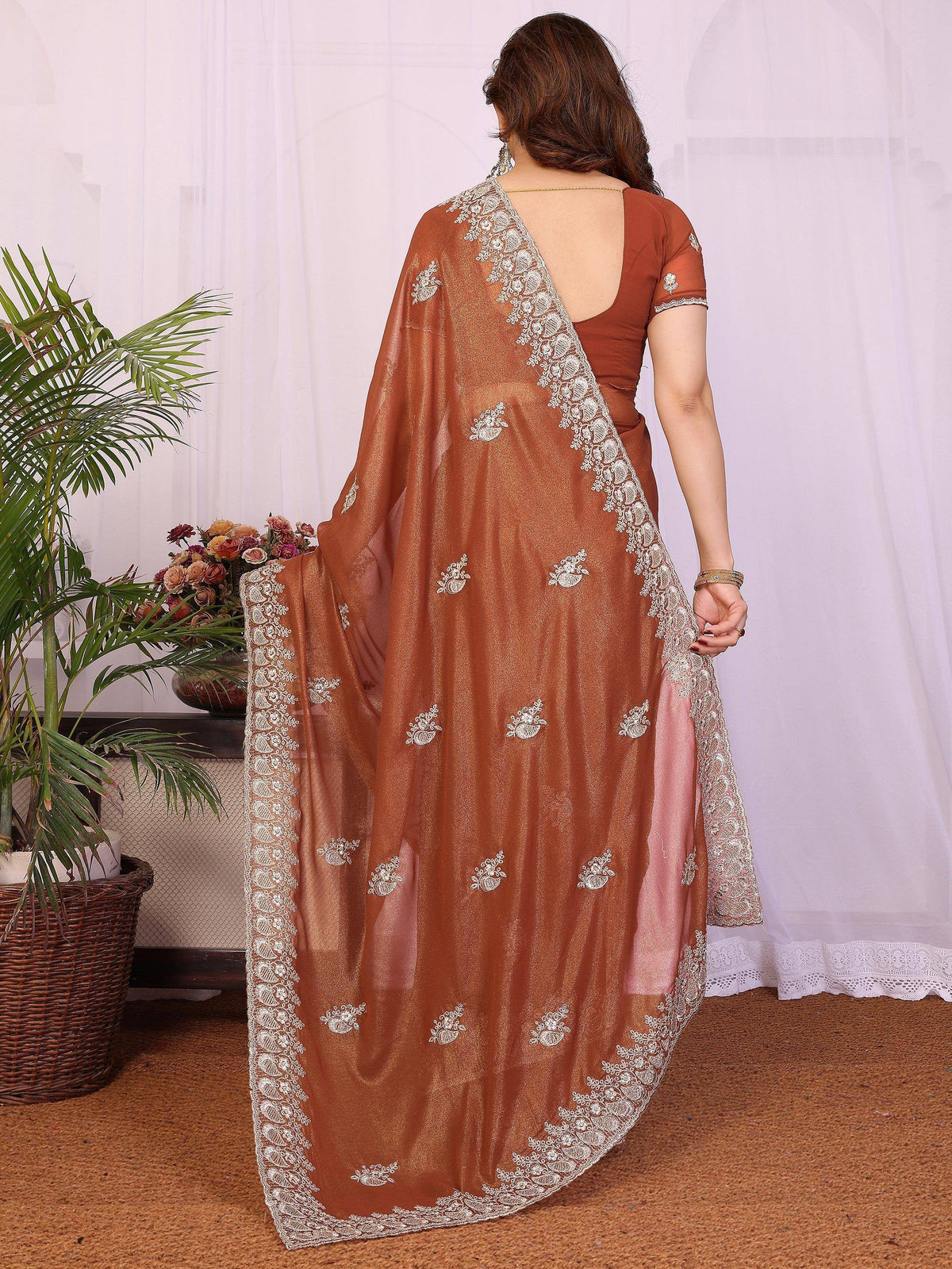 Back view of a woman wearing a brown designer saree with silver embroidered borders