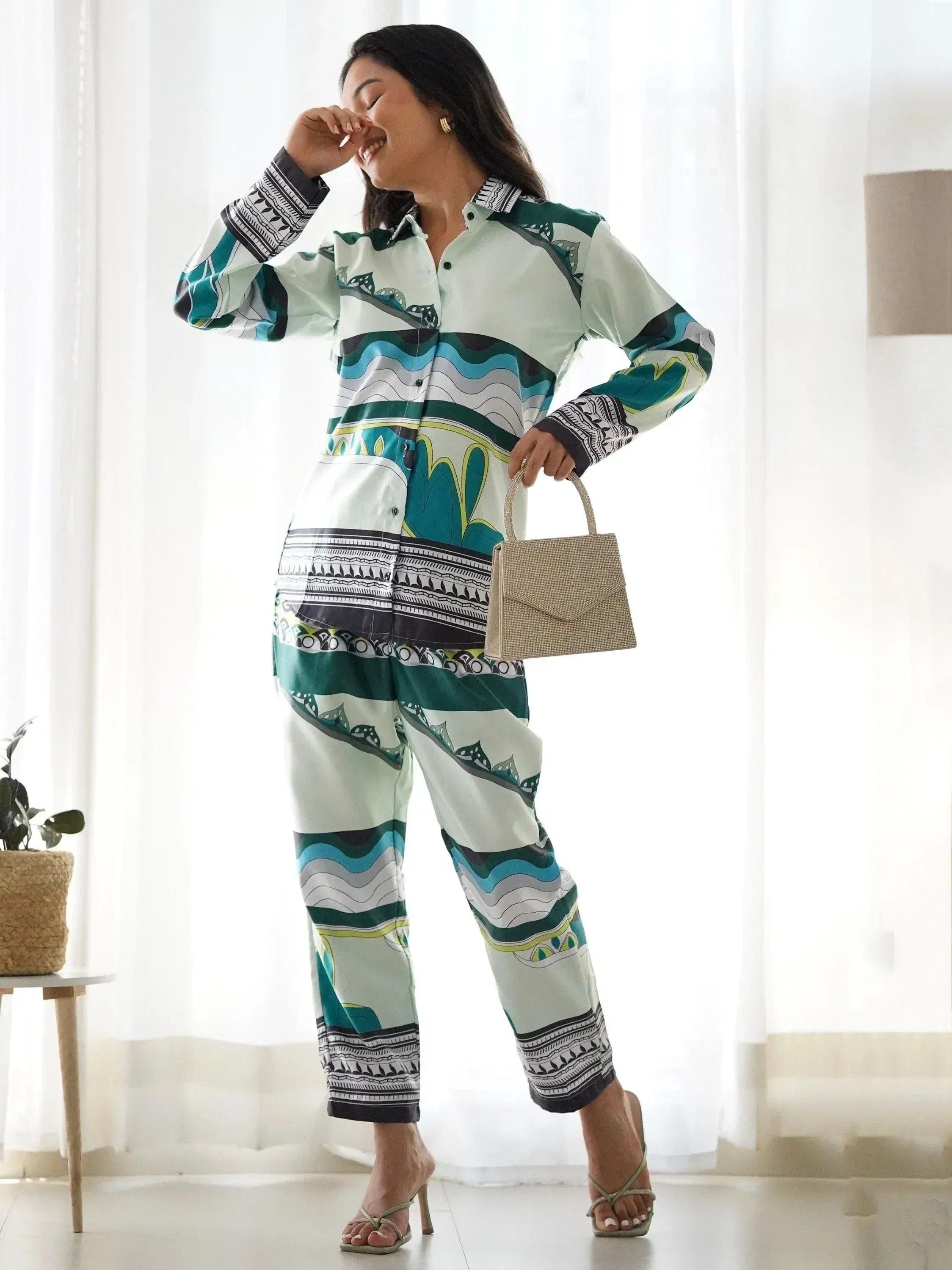 Woman in printed ethnic kurta pants set with geometric patterns, holding handbag, stylish Indian wear