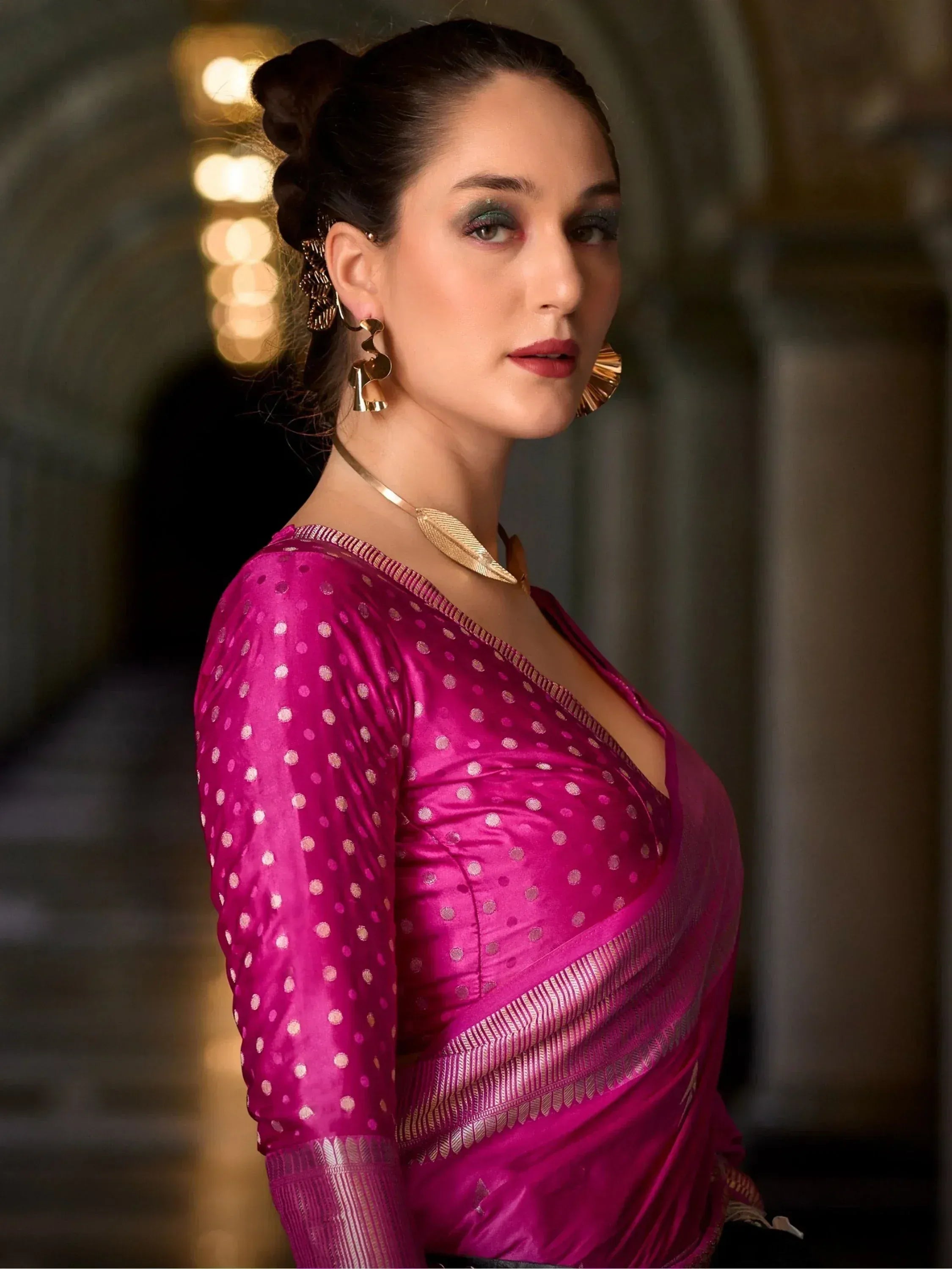 Woman in vibrant pink polka dot saree with gold jewelry, elegant ethnic wear for special occasions