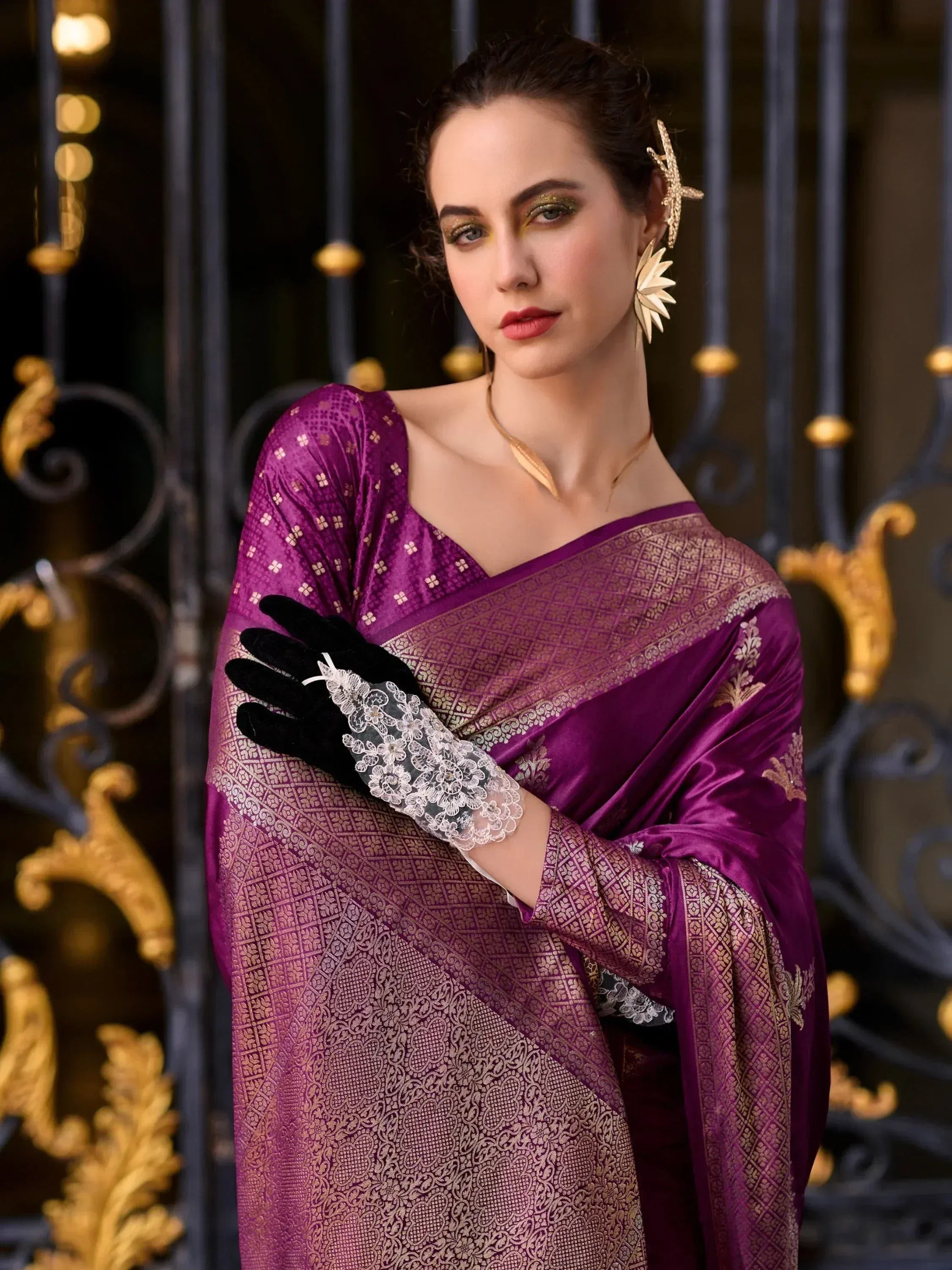 Purple designer saree with gold embroidery, lace gloves, and statement earrings for ethnic occasions