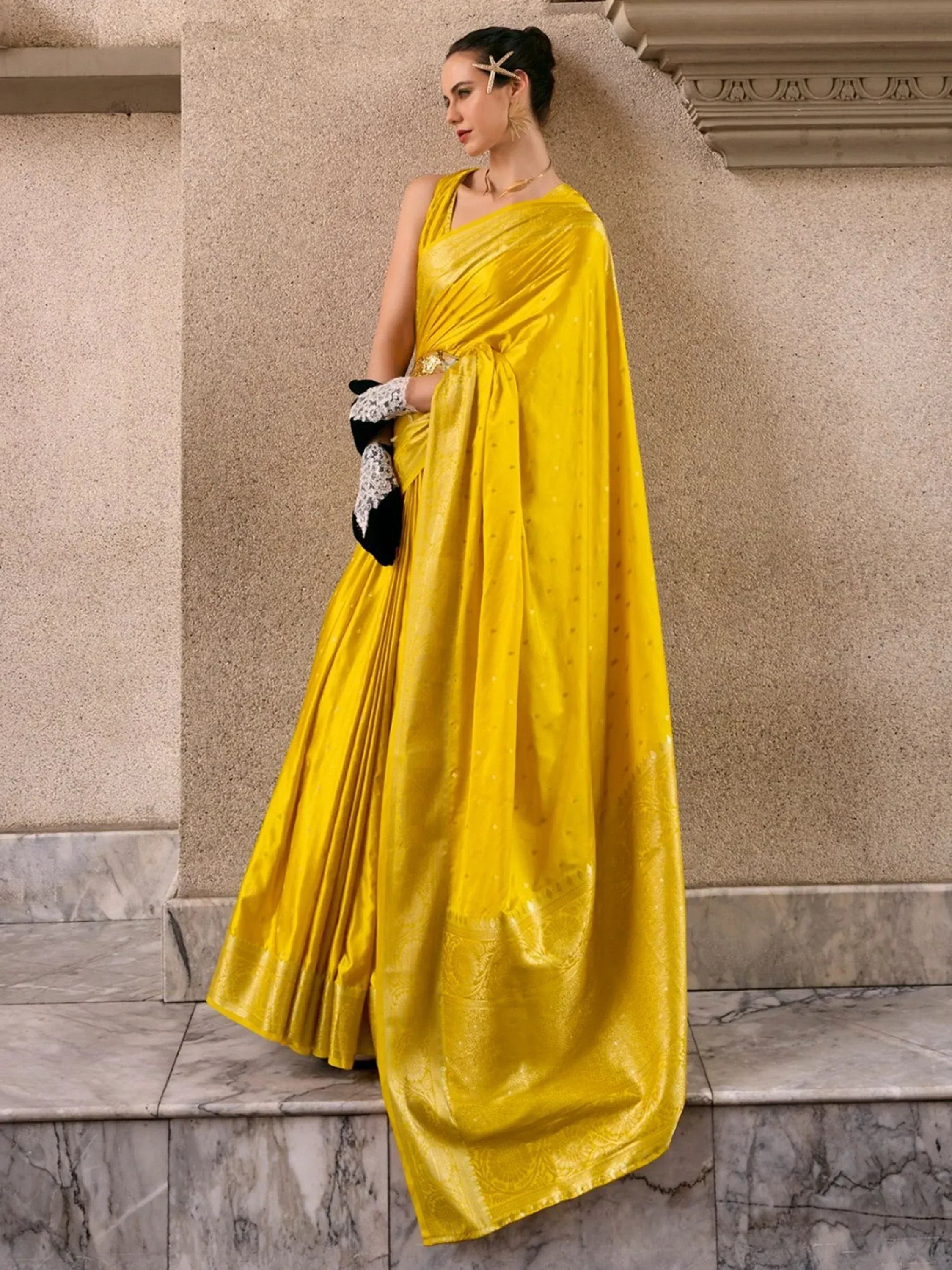 Vibrant yellow designer saree with subtle dot pattern, styled with black lace gloves and gold accessories