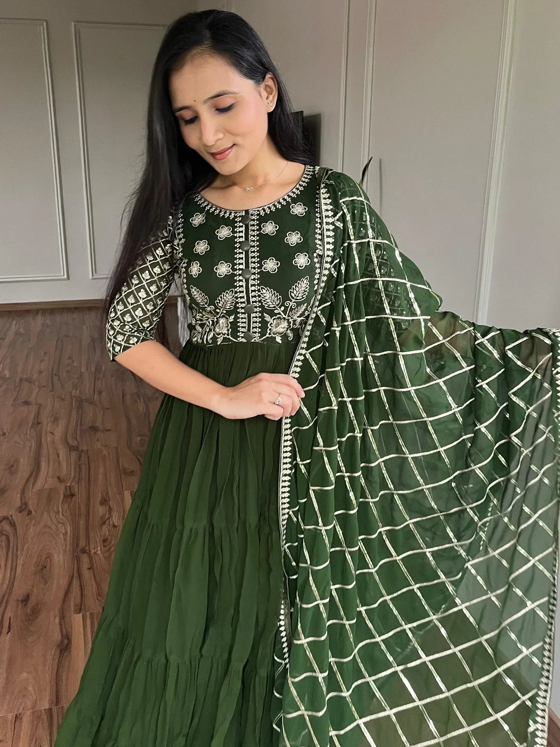 Green embroidered anarkali gown with gold floral motifs and net dupatta, ideal for festive occasions