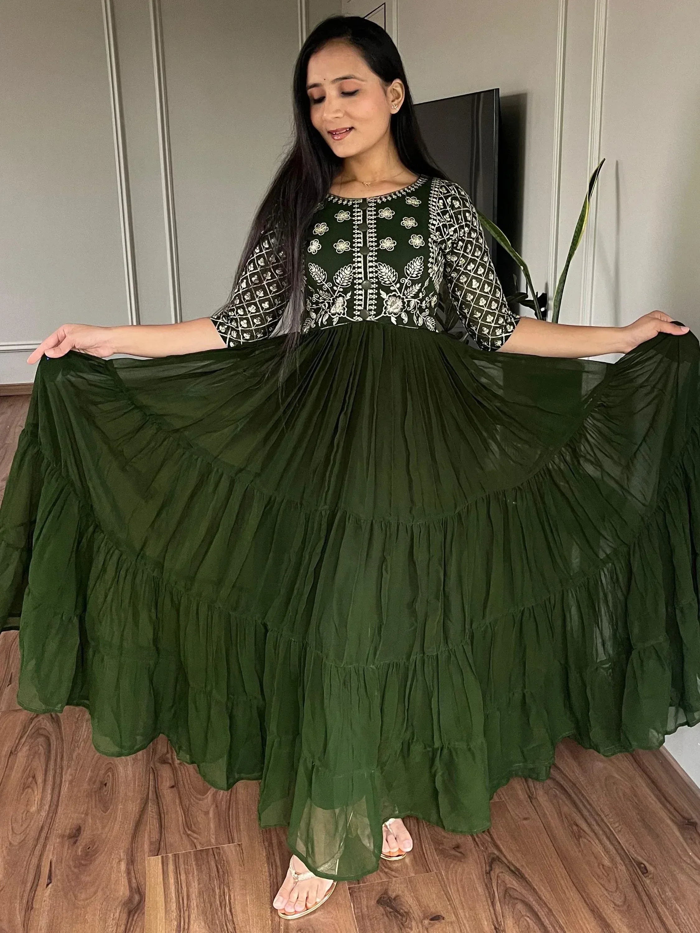 Woman in olive green embroidered ethnic gown with tiered ruffle skirt, showcasing flowy design