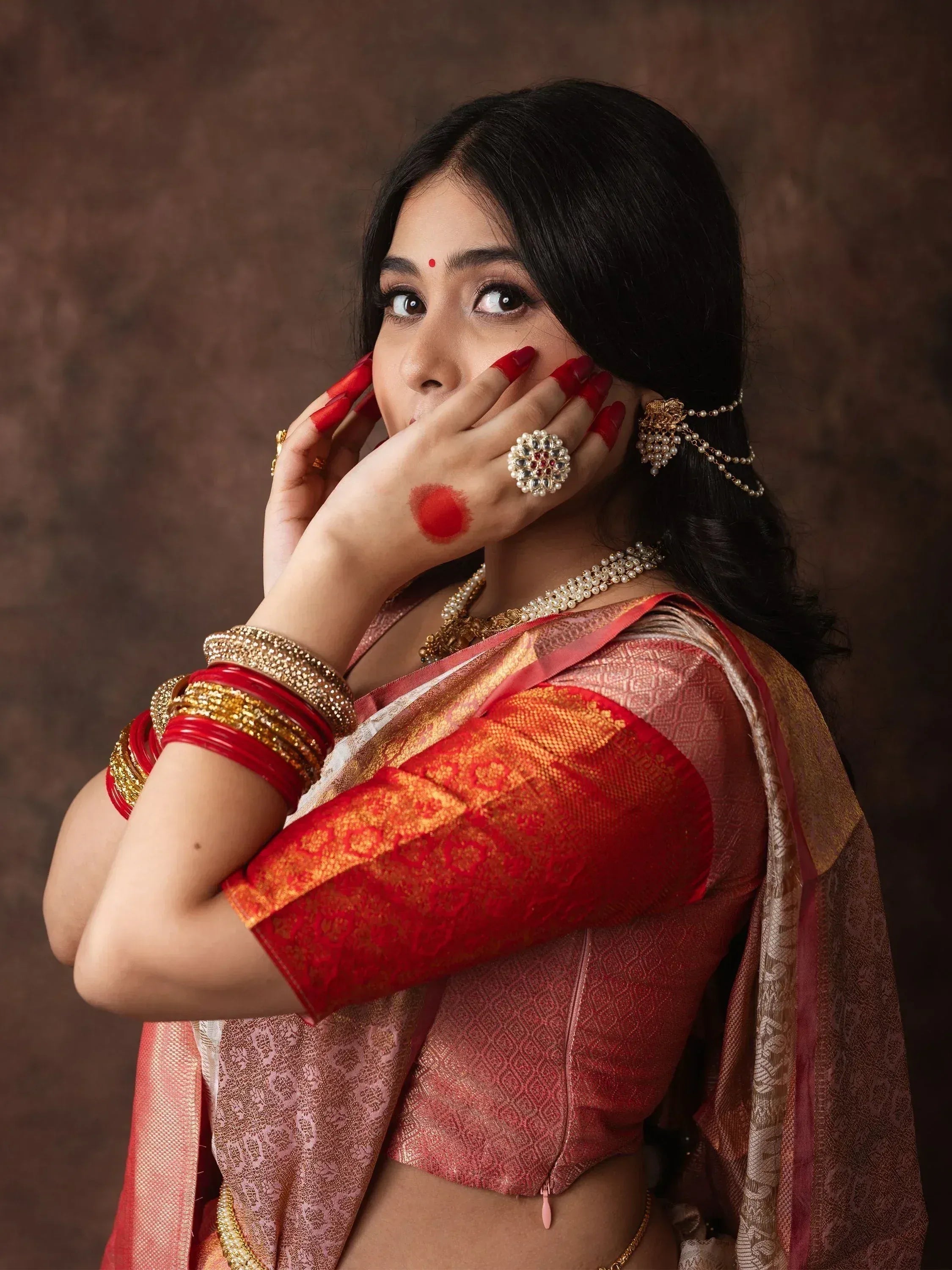 Woman in traditional red and gold saree with ethnic jewelry, perfect for Indian weddings or festivals