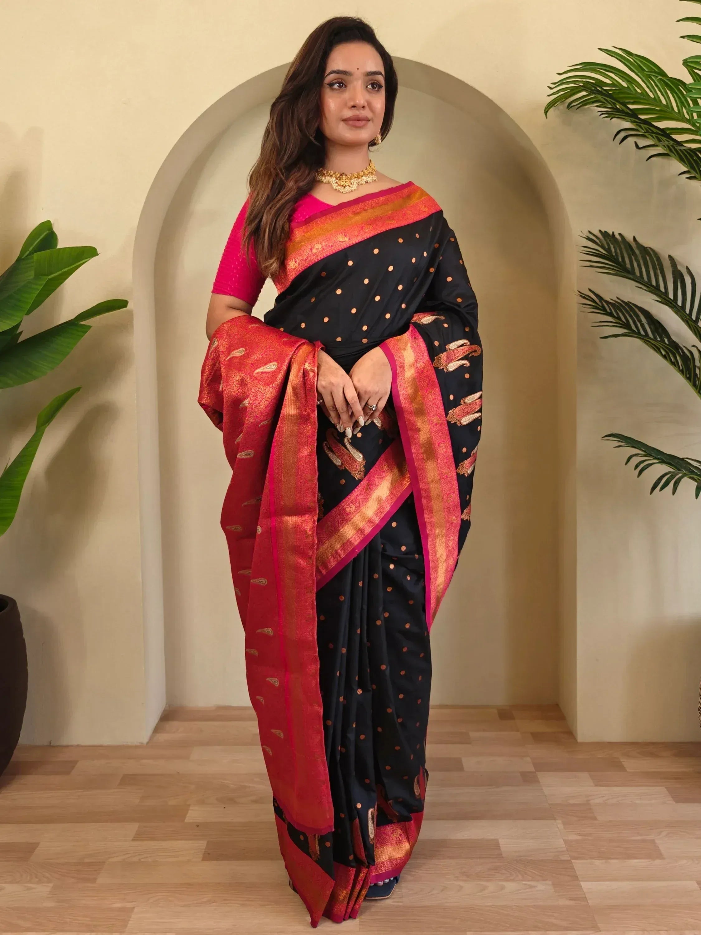 Black and red designer saree with gold motifs and pink blouse, styled for ethnic occasions