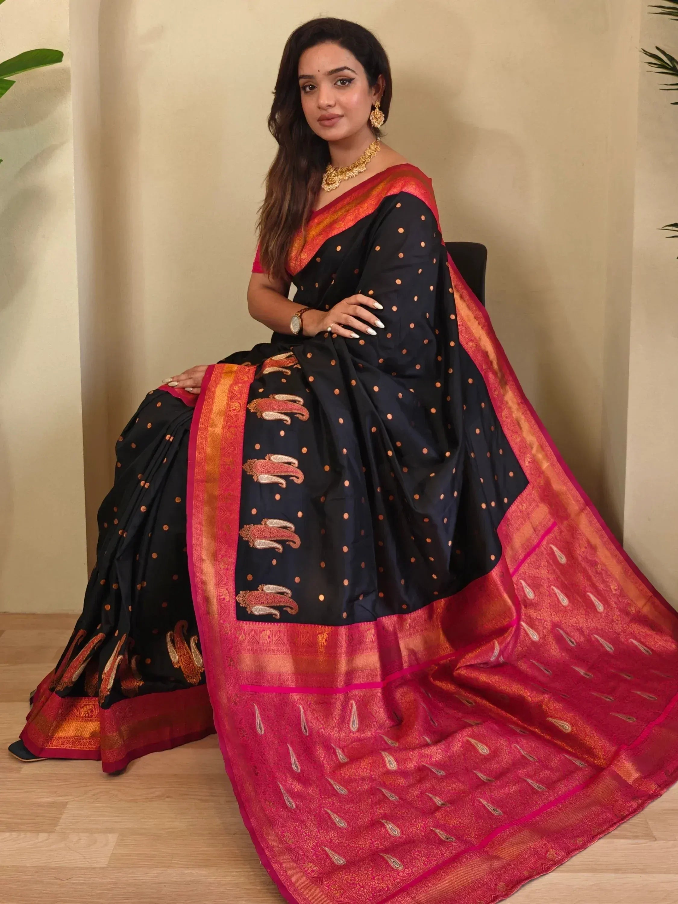 Black and pink ethnic saree with gold polka dots and paisley border, perfect for Indian occasions