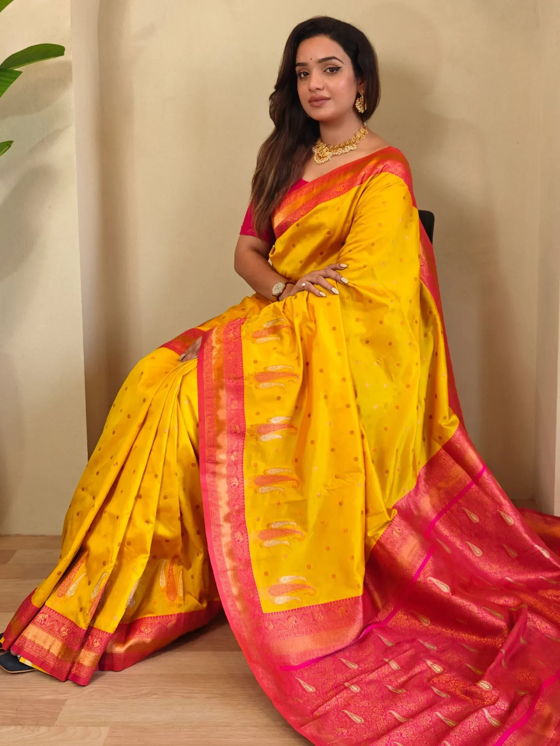 Yellow and pink designer saree with intricate patterns and gold jewelry
