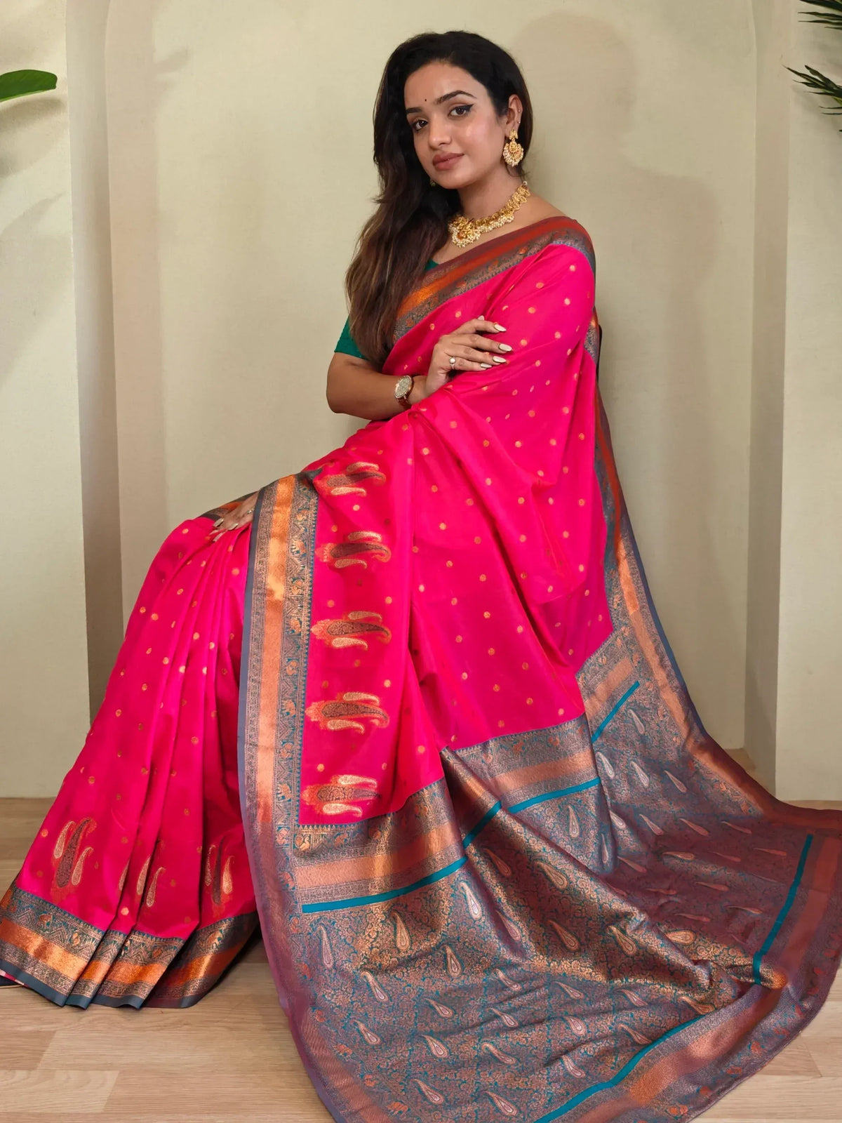 Woman in vibrant pink ethnic saree with gold paisley border, styled for Indian occasions