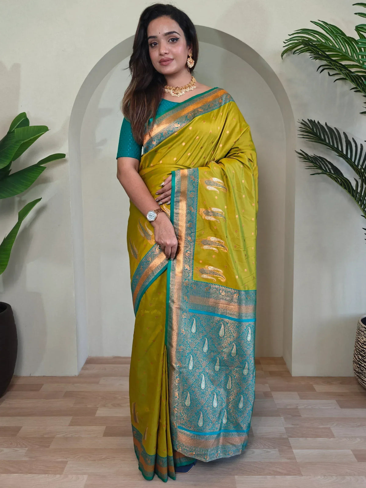 Woman in vibrant yellow and teal silk saree with gold zari border, perfect for Indian ethnic occasions