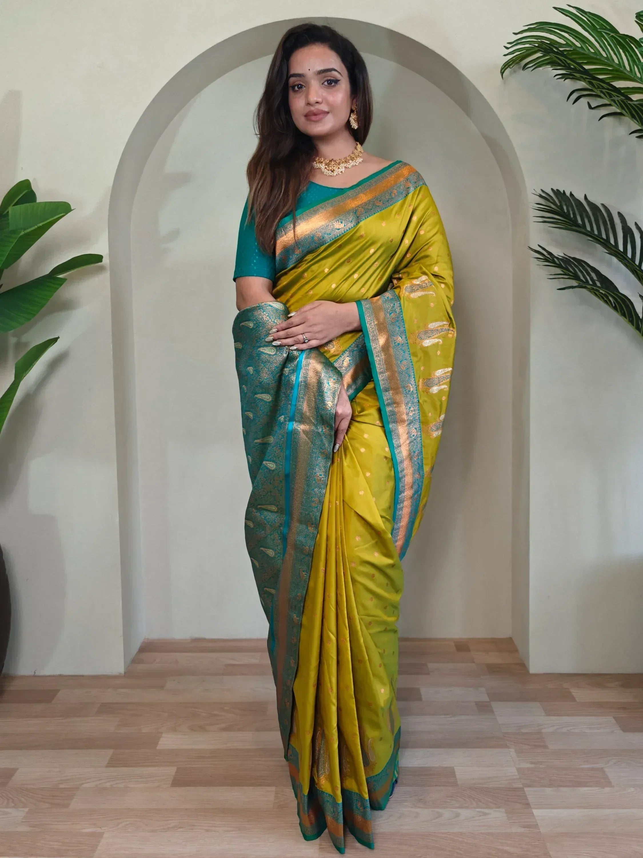 Woman in vibrant yellow and teal designer saree with gold border, perfect for Indian ethnic occasions