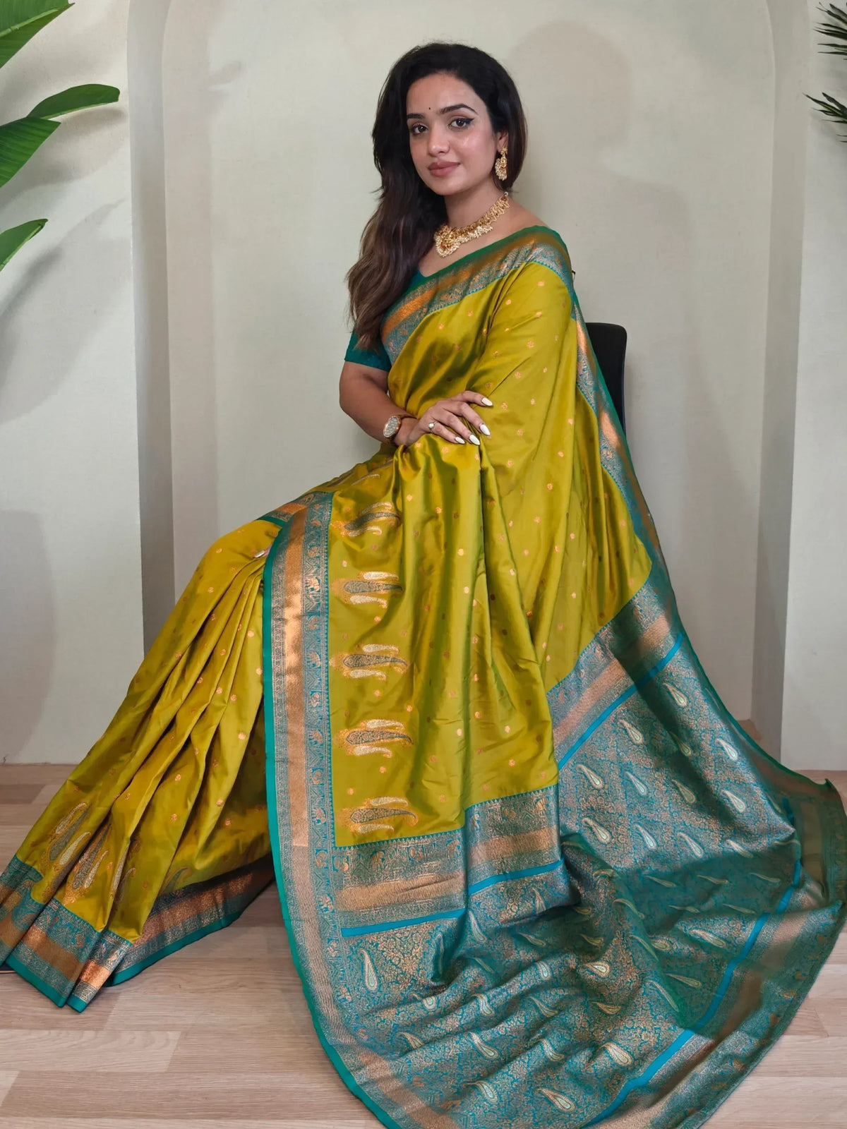 Woman in elegant green and teal designer saree with gold paisley border, perfect for Indian ethnic wear occasions.