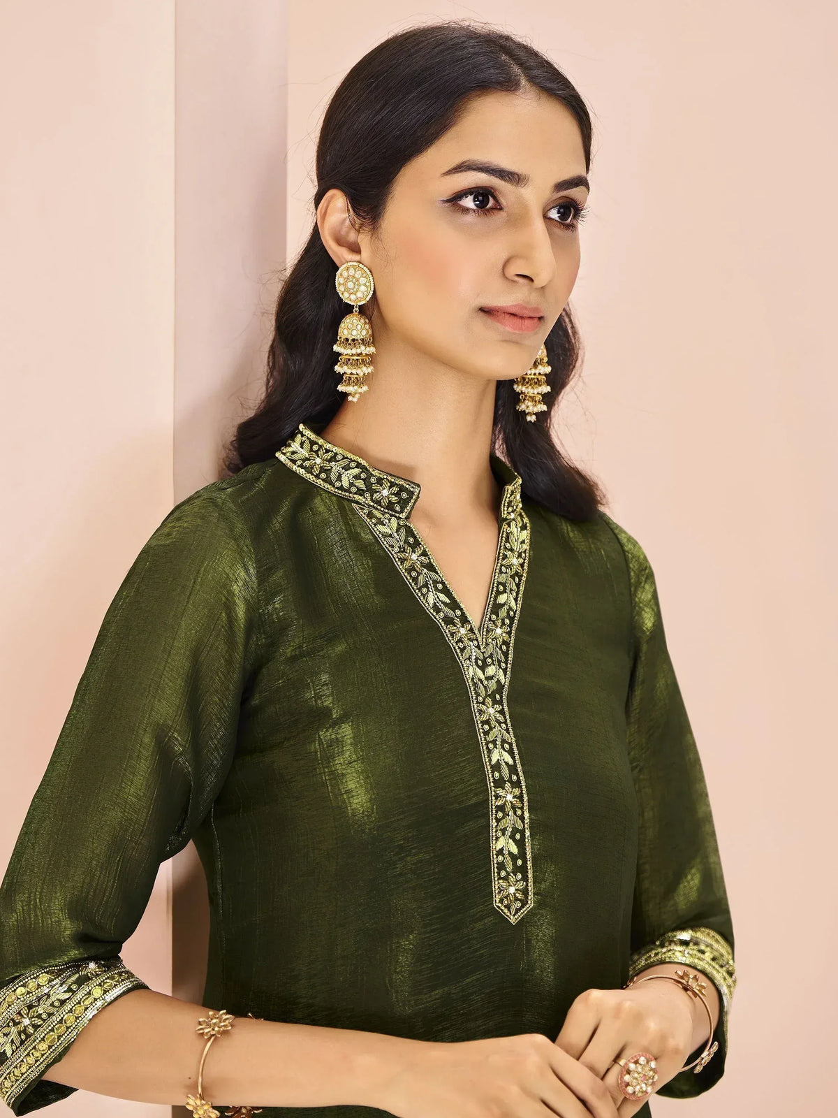Olive green ethnic kurti with gold embroidery, paired with jhumka earrings and traditional jewelry for festive occasions.