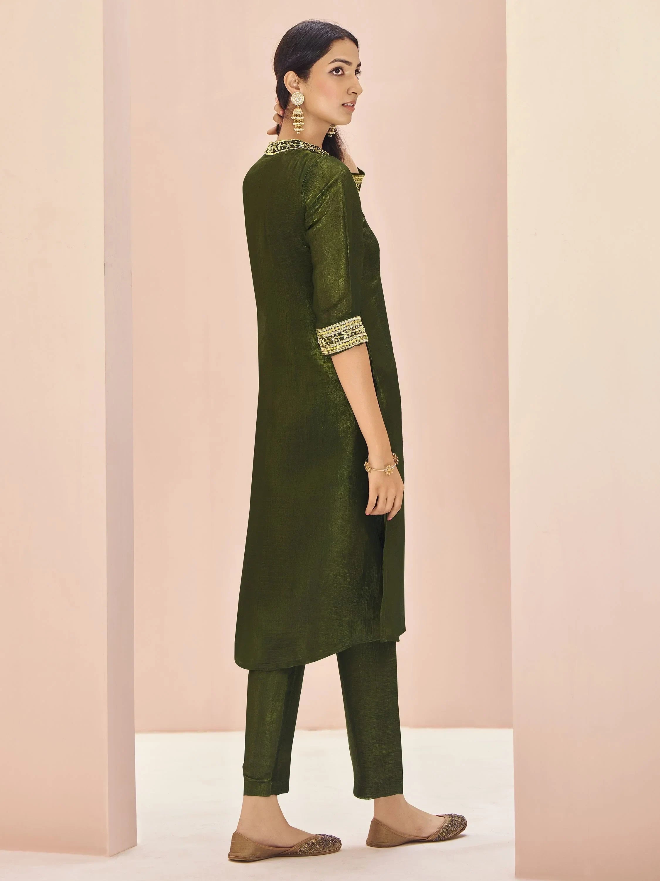 Woman in olive green straight kurta set with embroidered collar and sleeves, wearing ethnic earrings