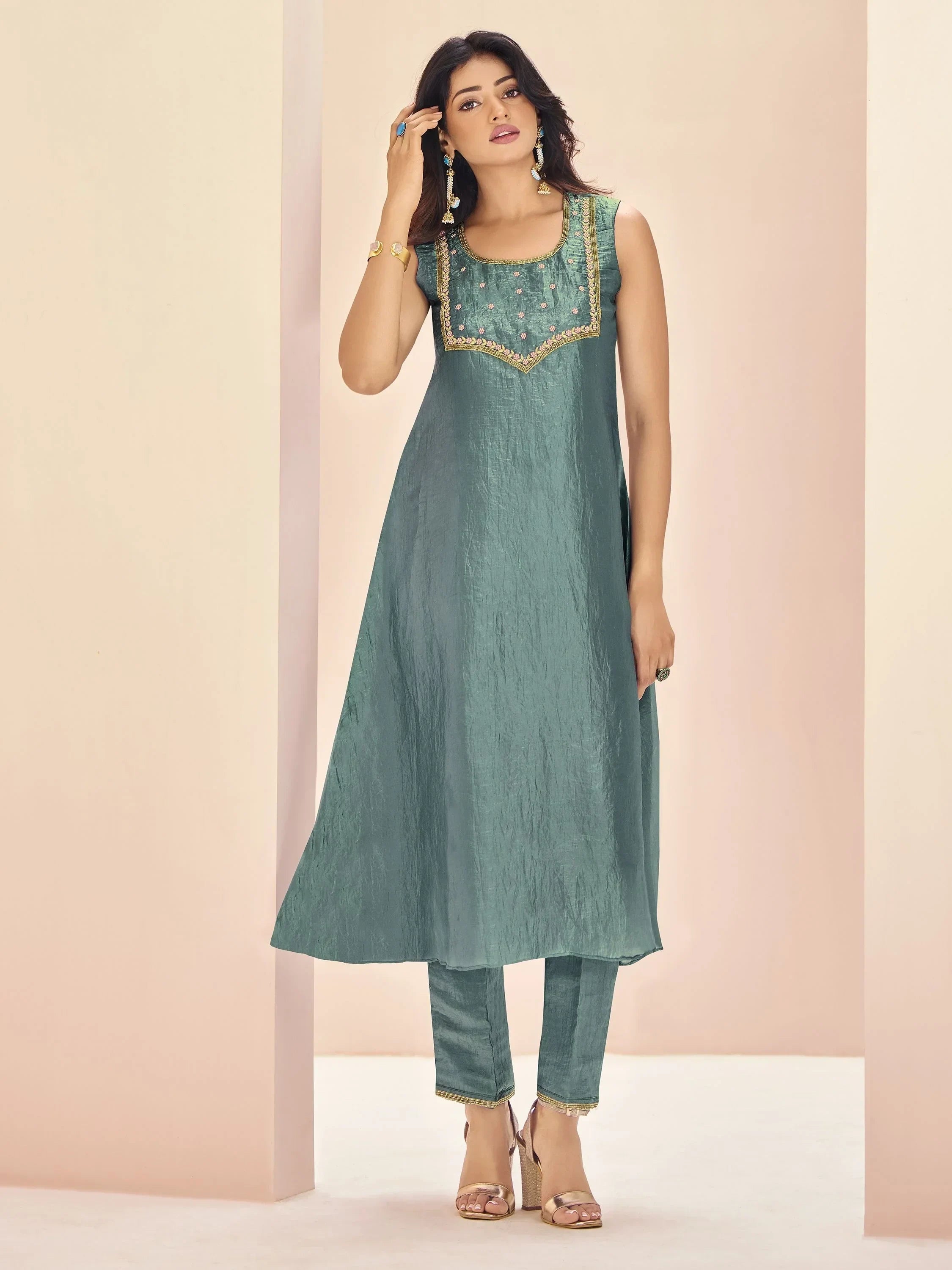 Woman wearing designer green ethnic straight kurta with embroidered yoke and matching pants.