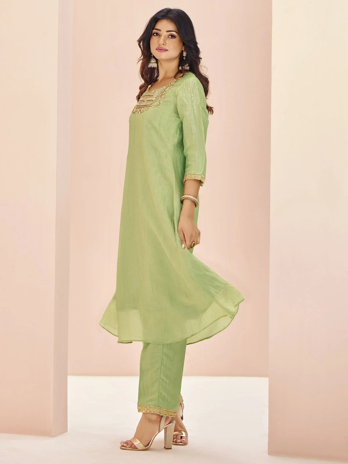 Light green ethnic kurti with gold embroidery and matching pants, styled for festive occasions.