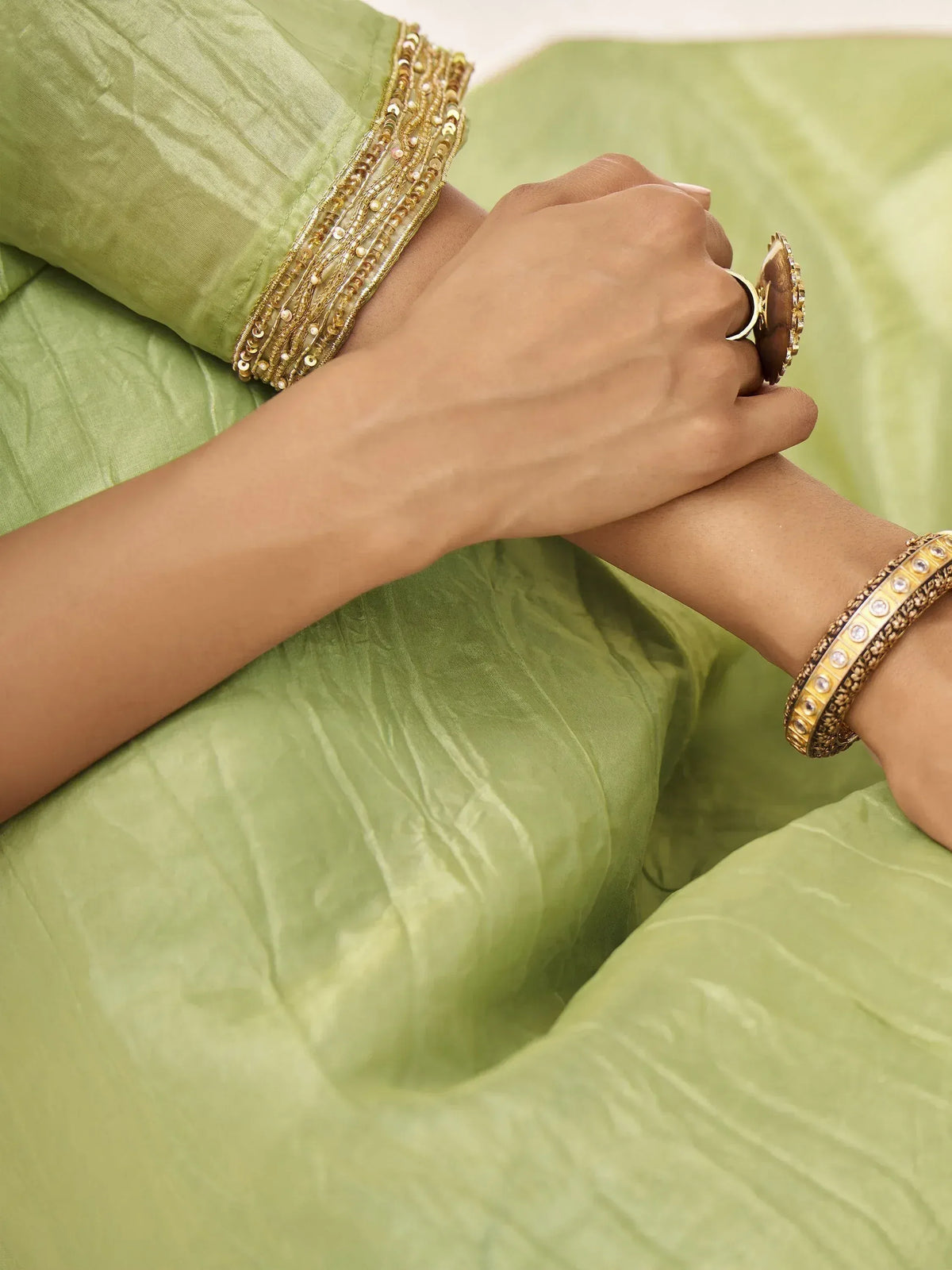 Elegant green ethnic wear with golden embellished sleeves and traditional jewelry