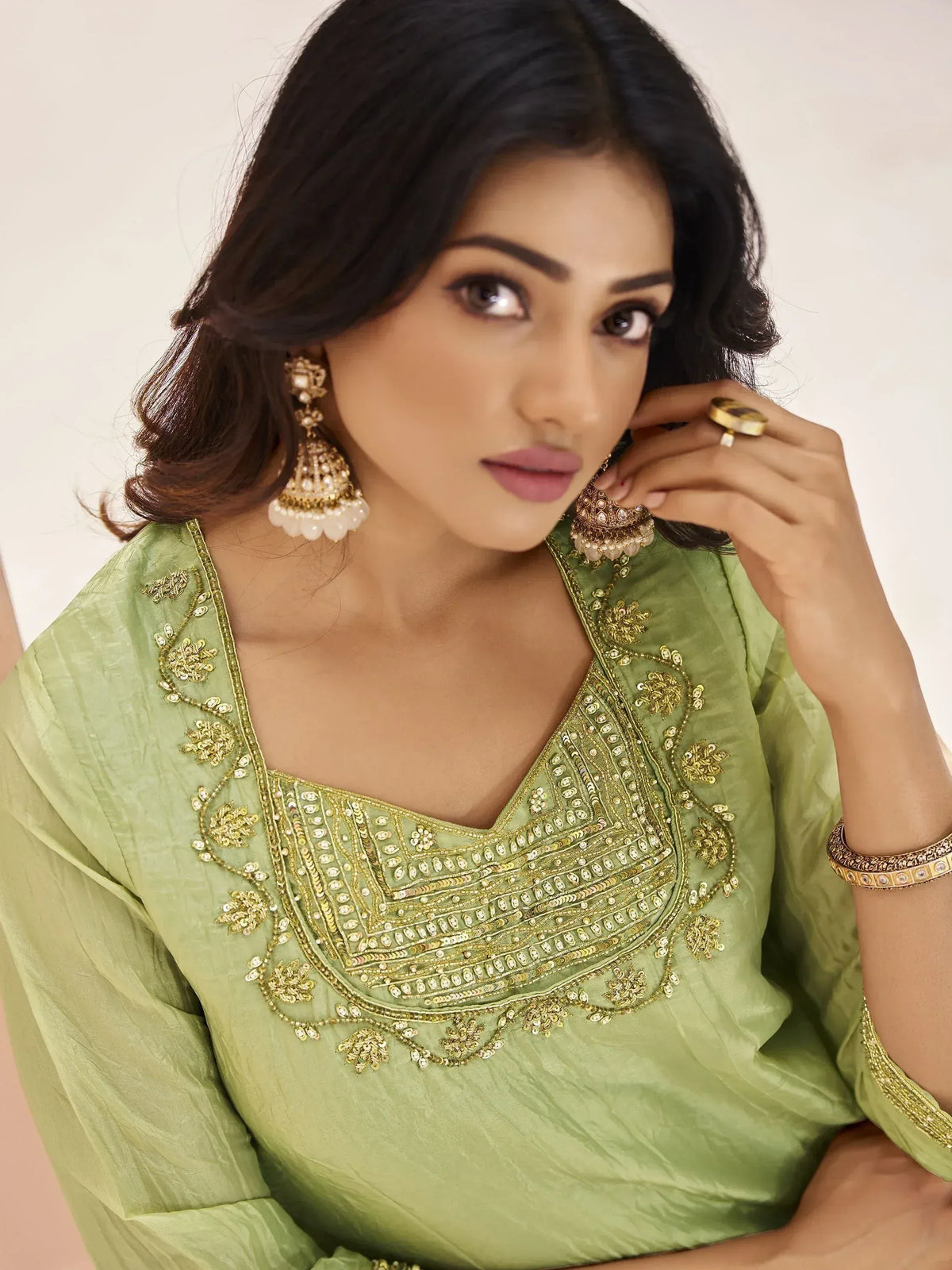 Woman in olive green ethnic kurti with gold embroidery and jhumka earrings, perfect for Indian festive wear.