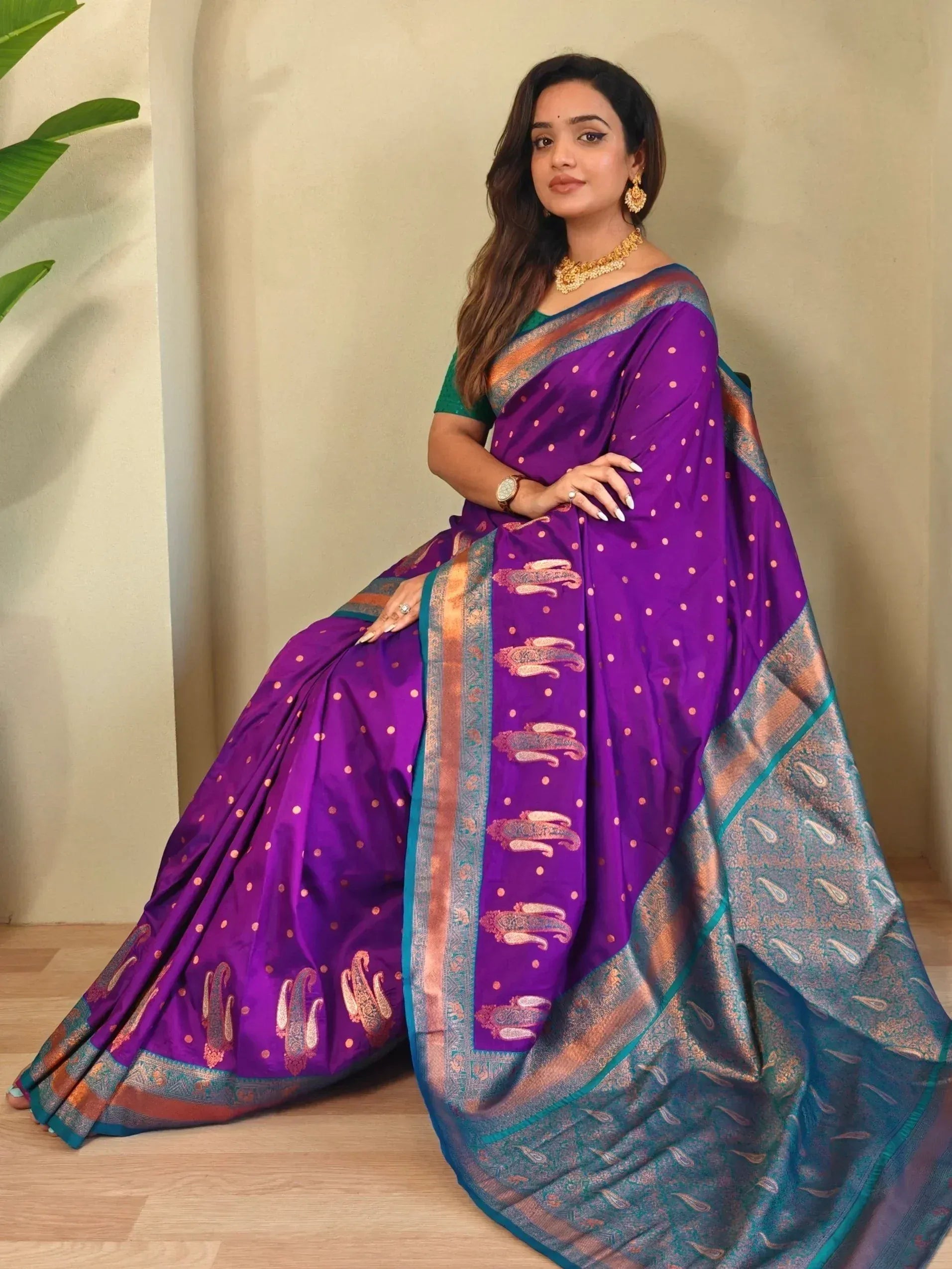 Purple ethnic saree with gold paisley motifs and teal border, paired with green blouse for traditional Indian wear