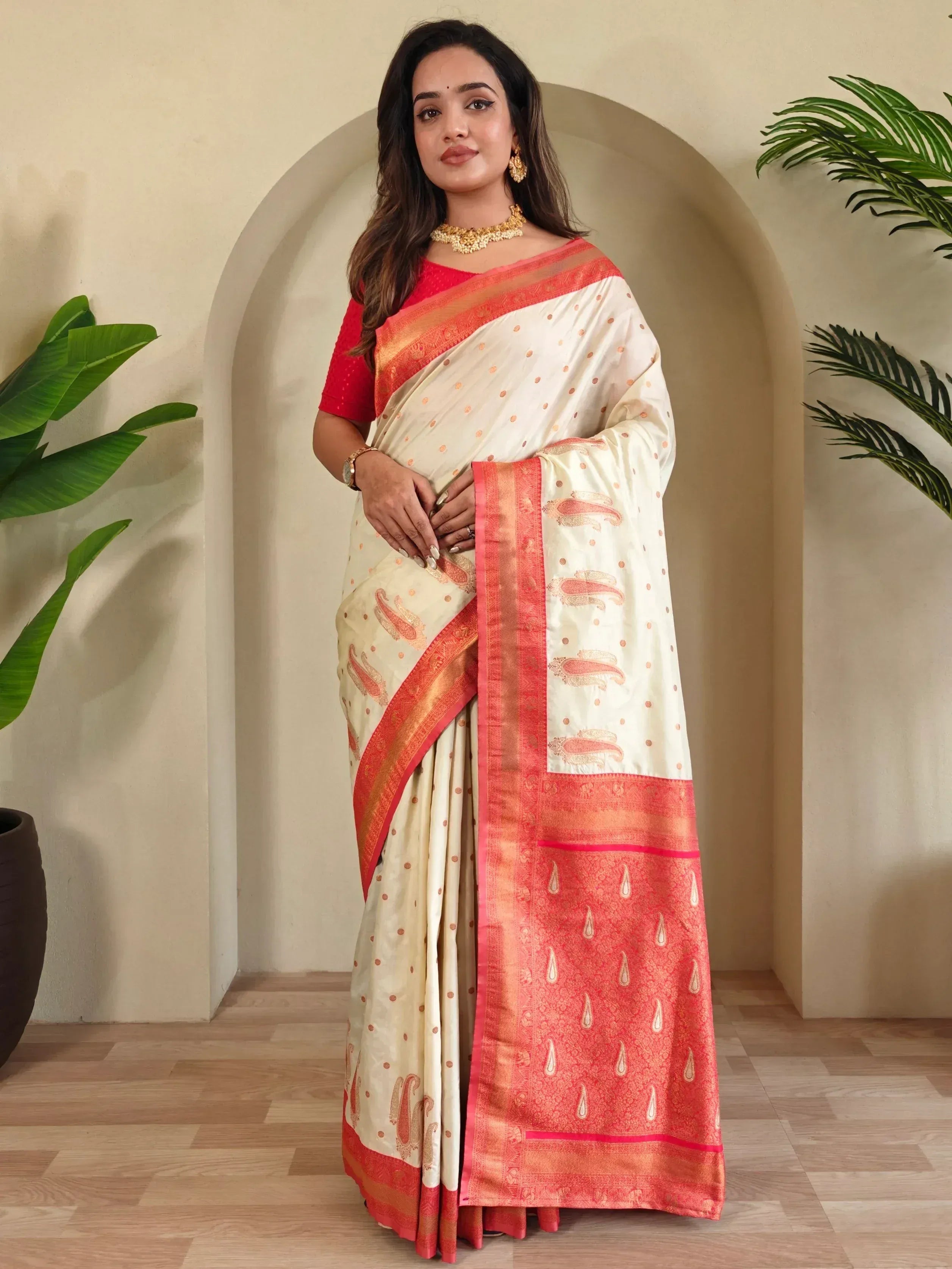 Cream and coral designer saree with paisley motifs and gold border, paired with red blouse for ethnic wear